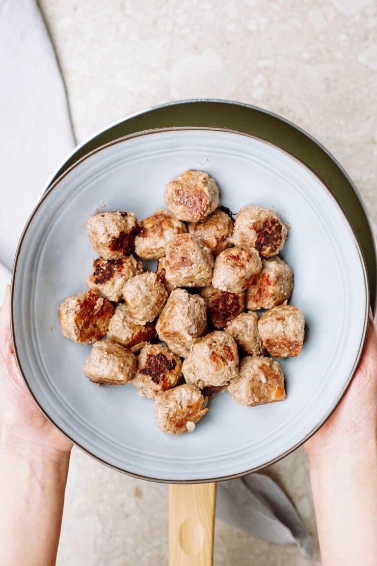 A plate of cooked meatballs held by a person.