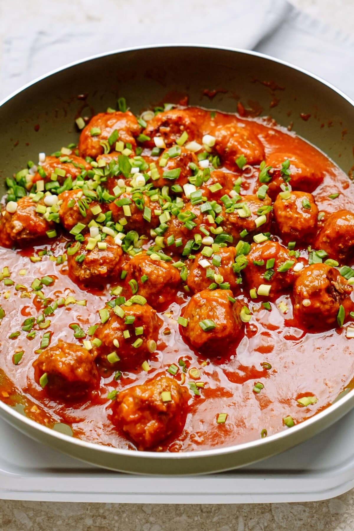 Meatballs in sauce garnished with chopped green onions.