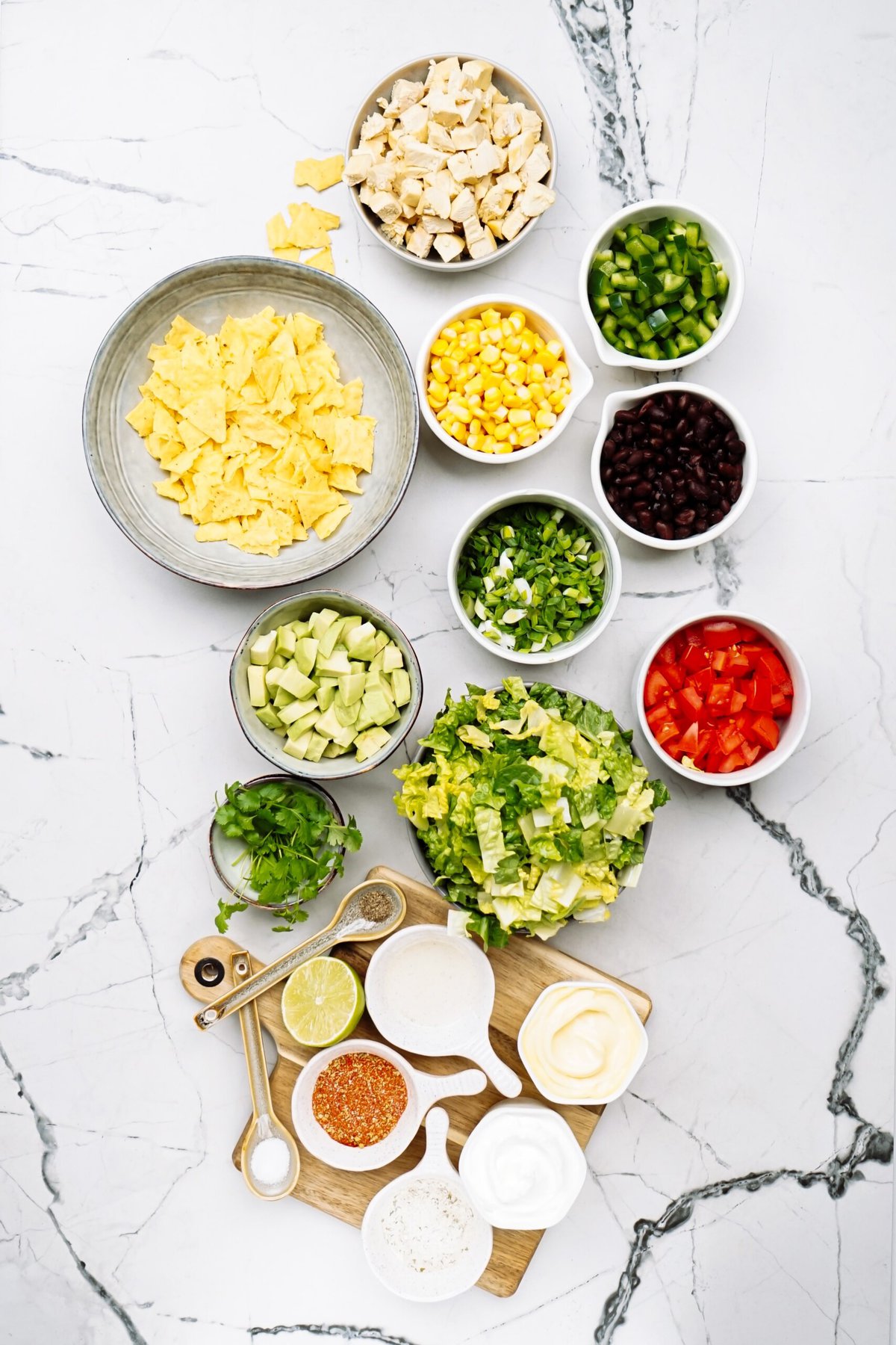 Various ingredients for a southwest salad arranged neatly on a marble countertop.