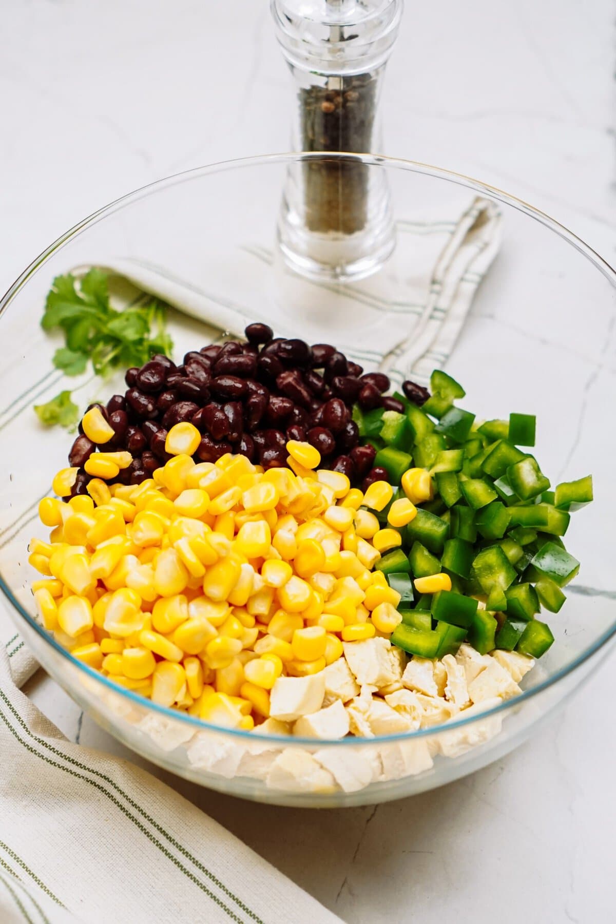 Ingredients for a mixed bean and vegetable southwest salad arranged separately in a glass bowl before mixing.