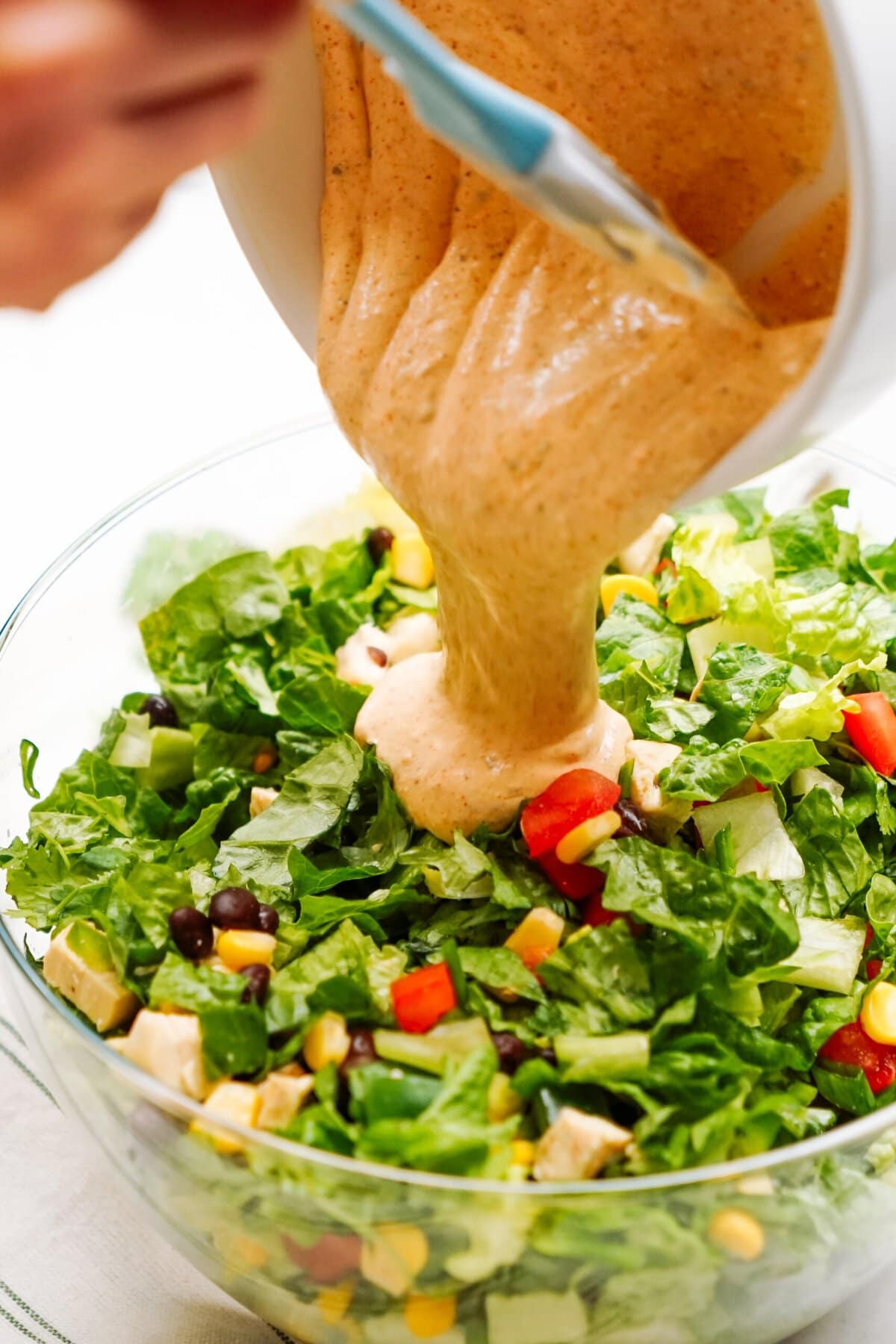Pouring dressing on a southwest salad.