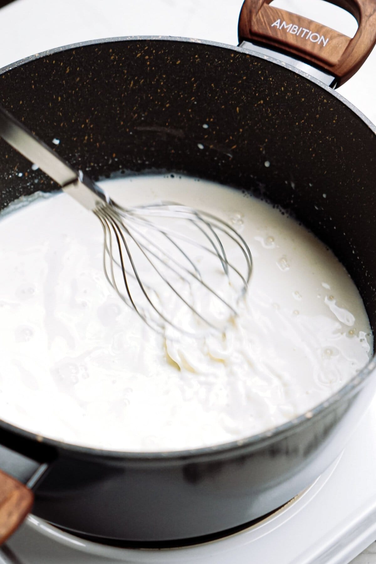Milk being whisked in a non-stick frying pan.