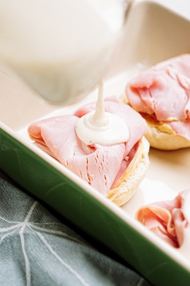 Pouring mayonnaise dressing on a ham sandwich.