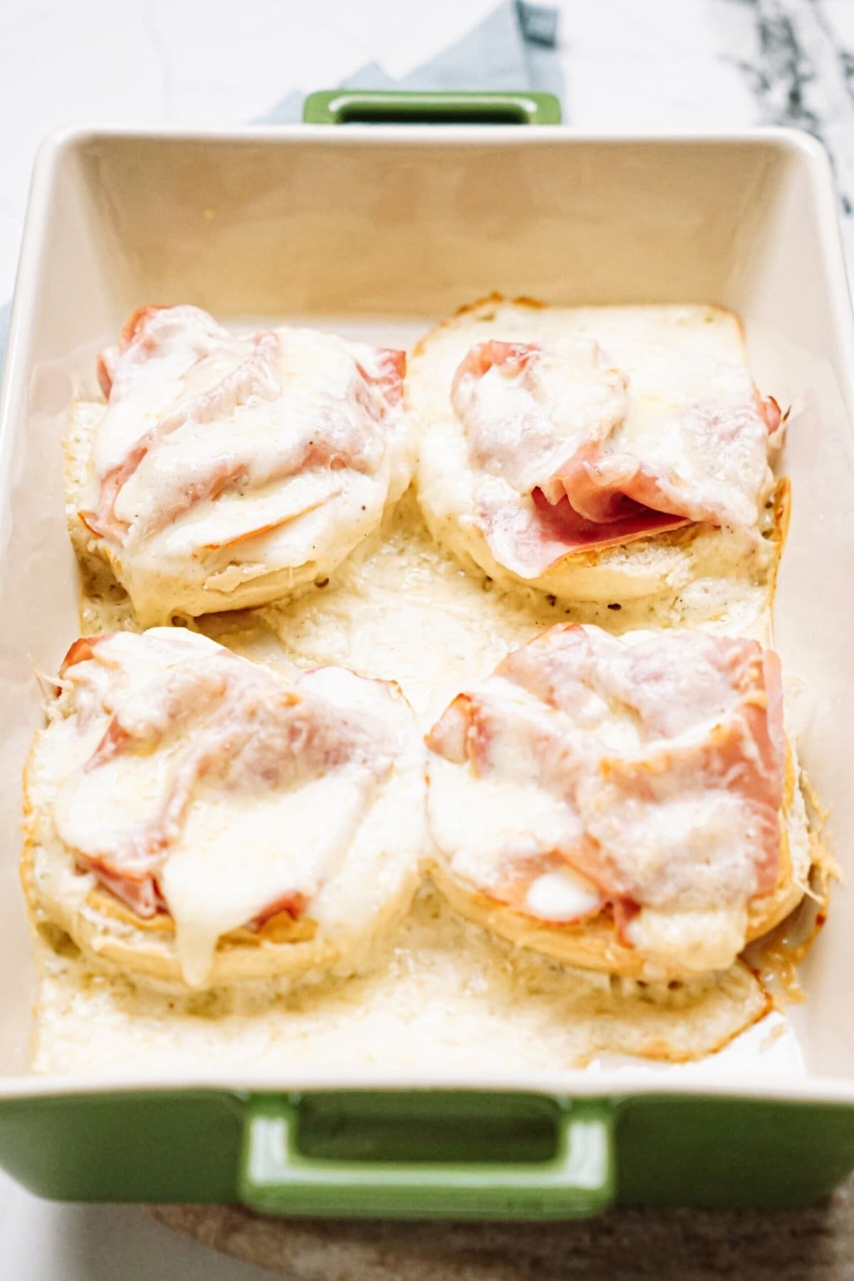 Baked croque Monsieur topped with ham and melted cheese in a casserole dish.