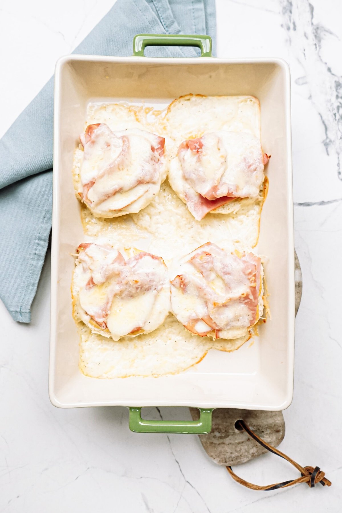 Open-faced sandwiches with ham and melted cheese in a baking dish.
