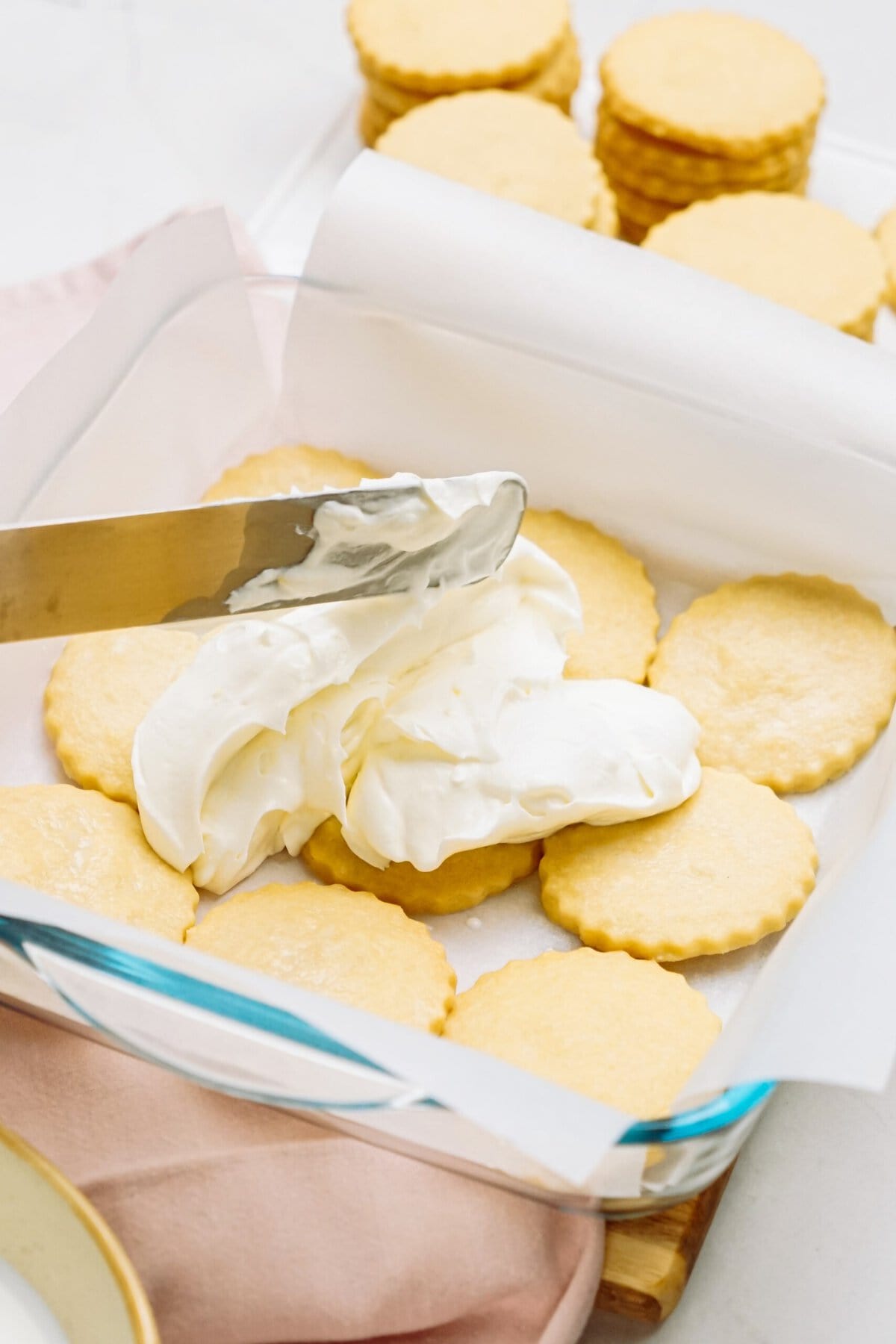 Spreading lemon icebox cake filling over a layer of shortbread cookies
