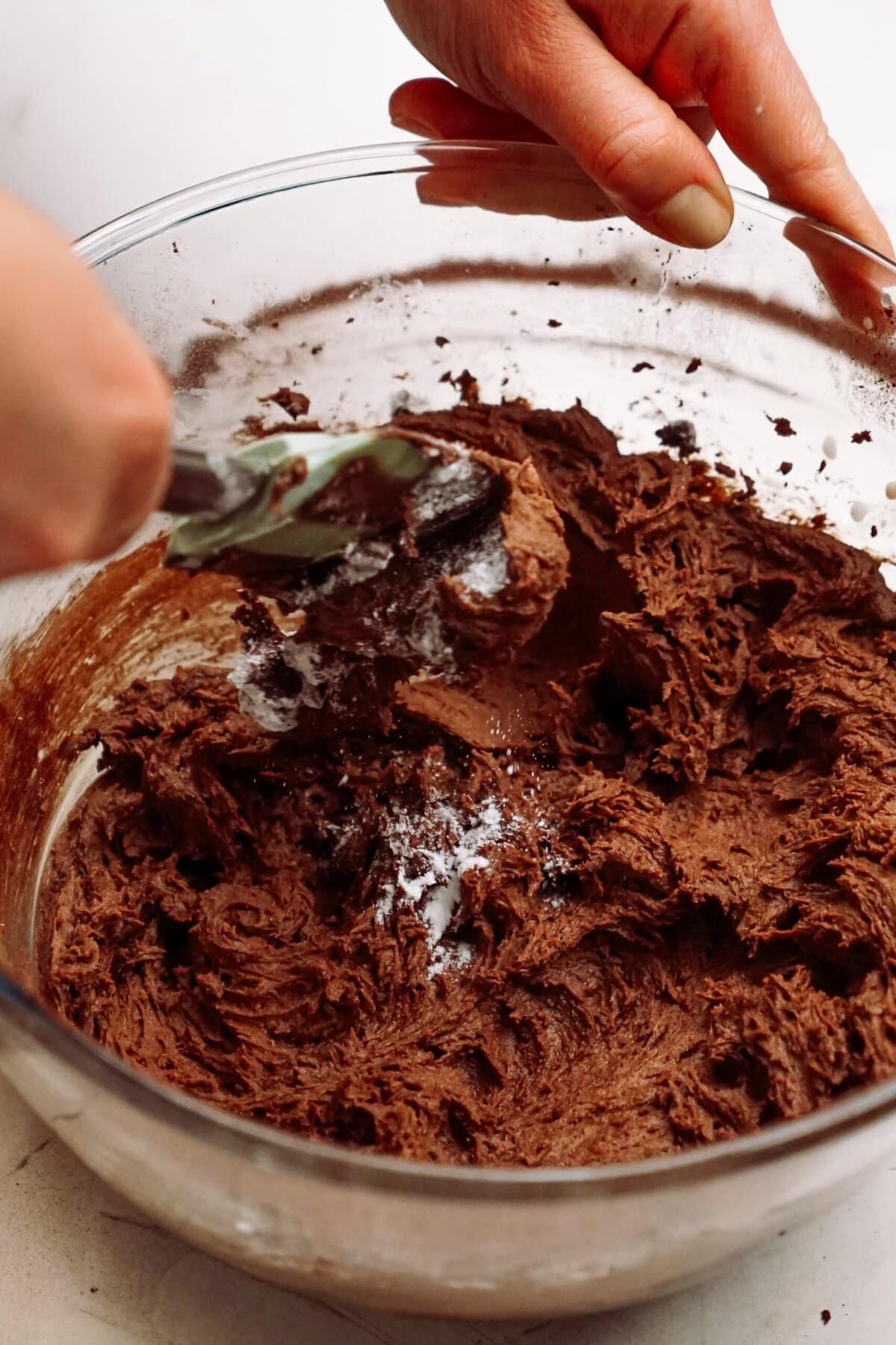 Mixing chocolate batter in a glass bowl.