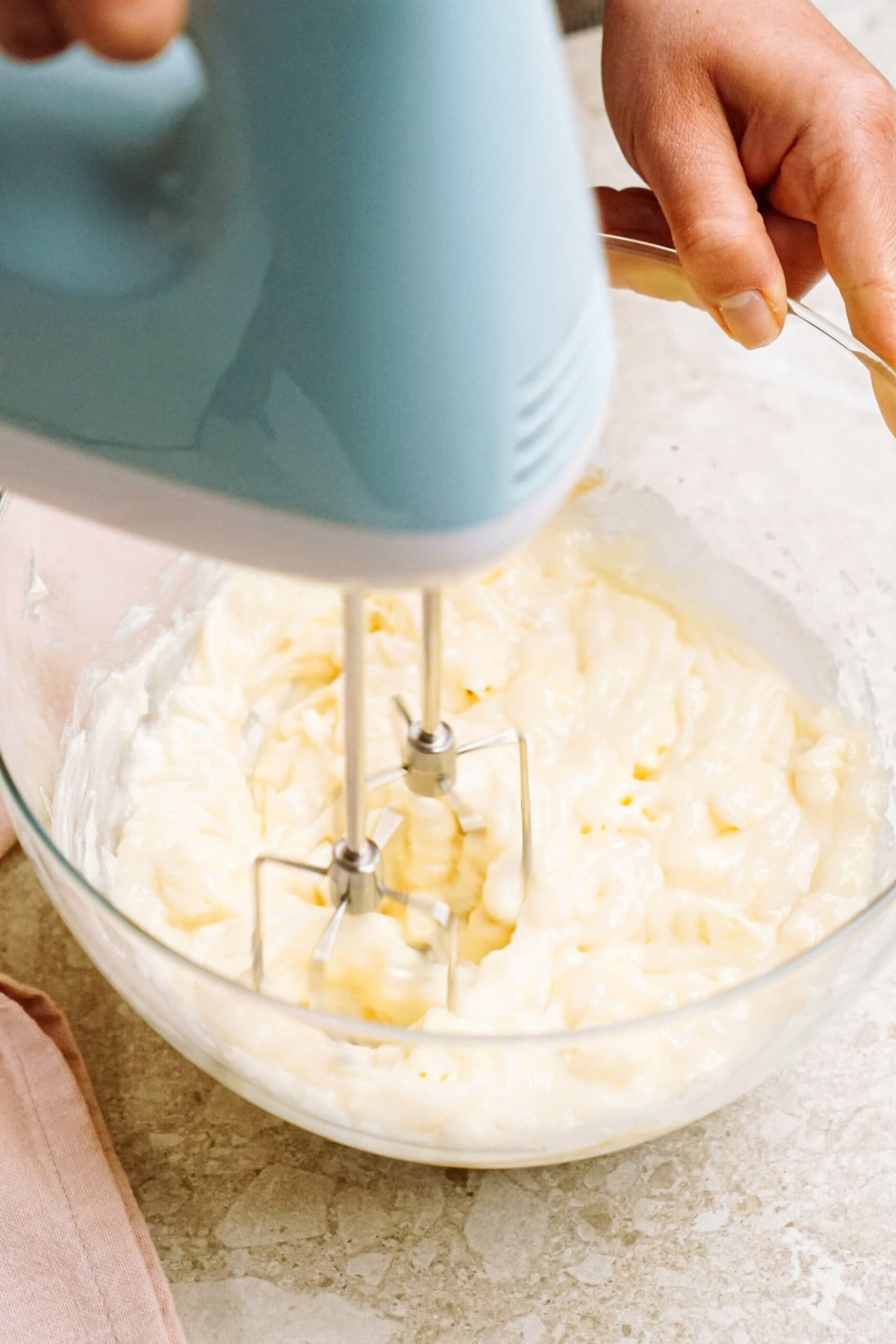 person using a hand mixer to whip into frosting