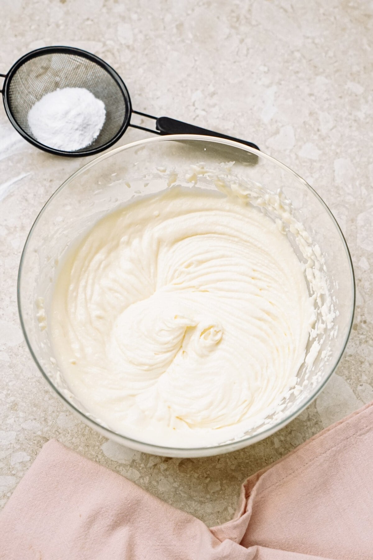 cream cheese frosting in a glass bowl on a counter top