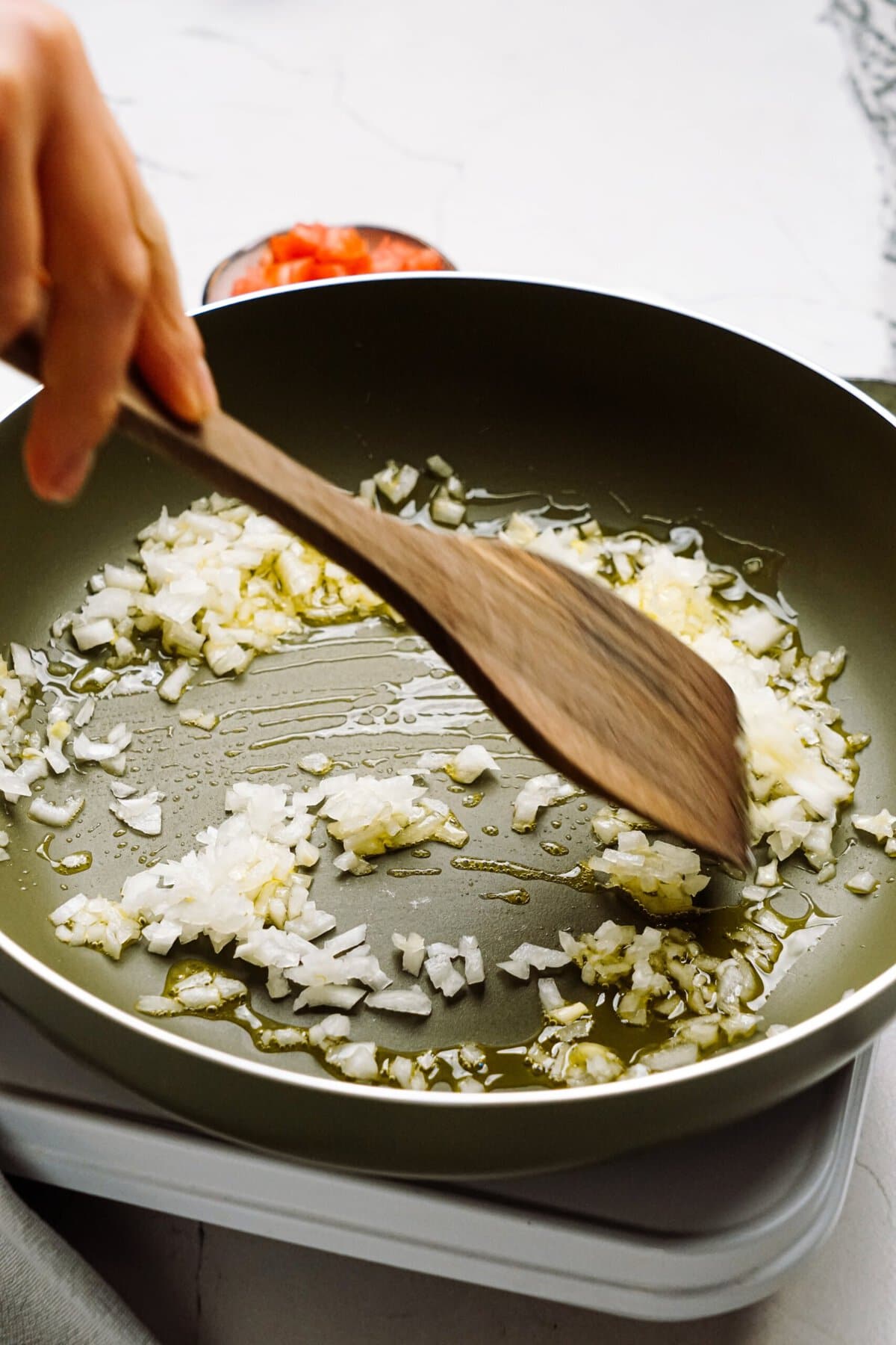 a person sautéing onions in a skillet 
