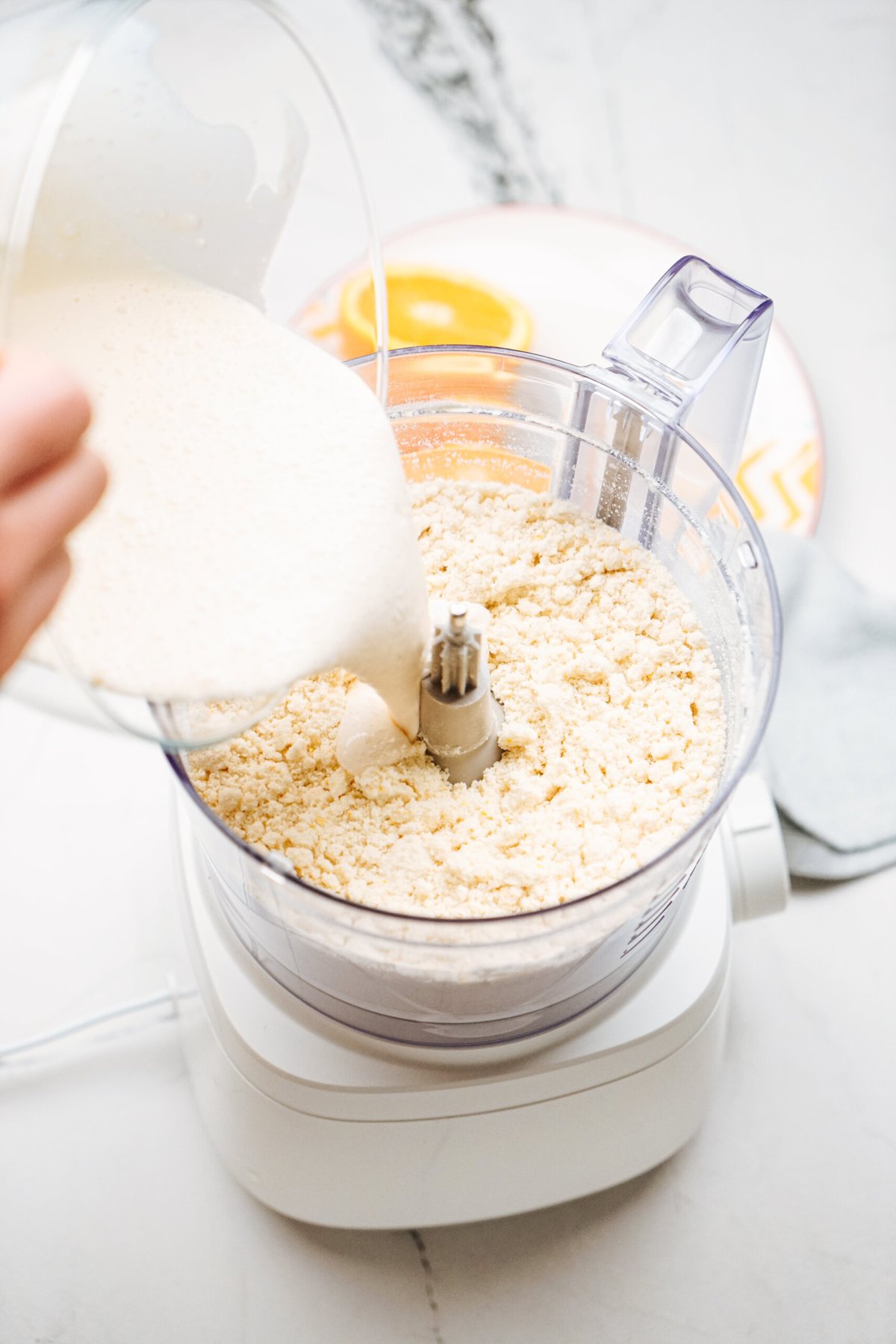 a person adding ingredients to a food processor