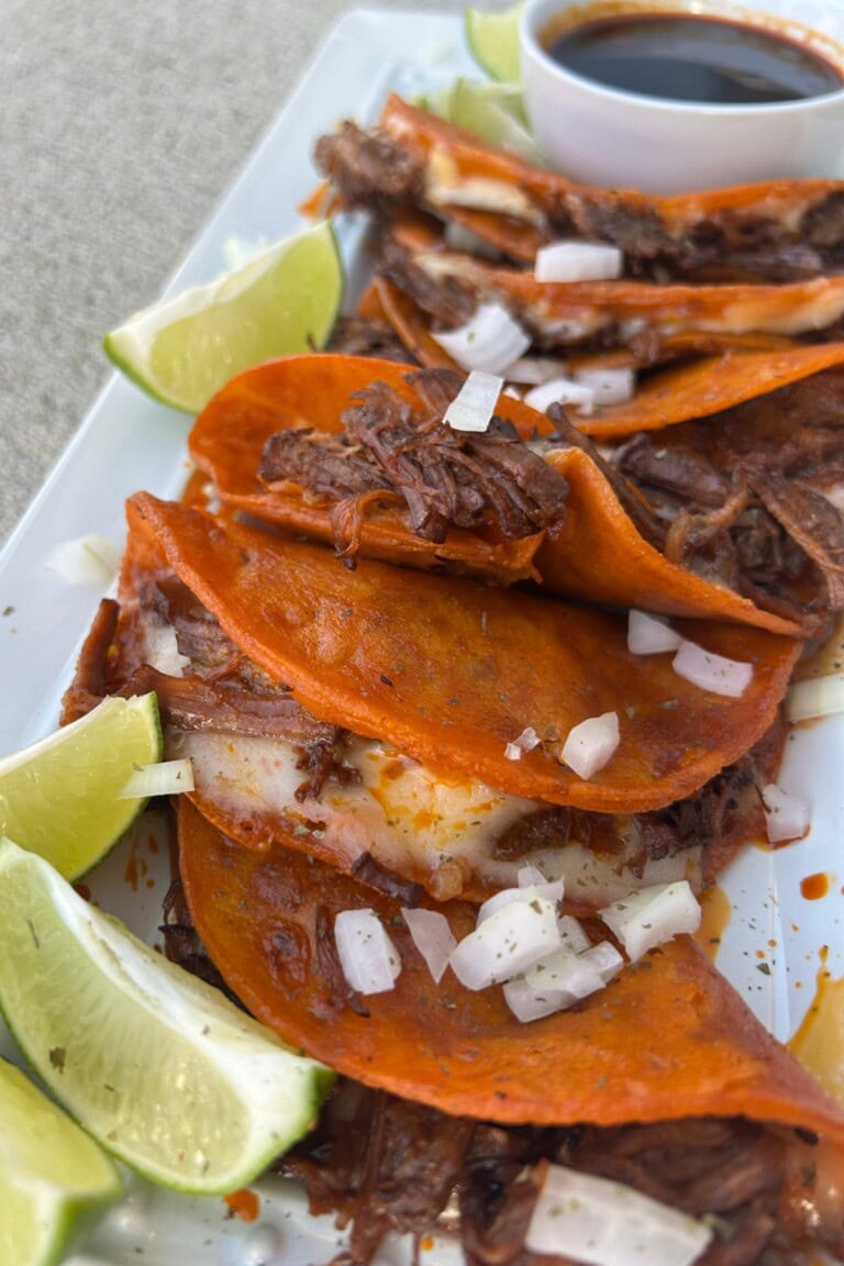 birria tacos on a plate with lime wedges