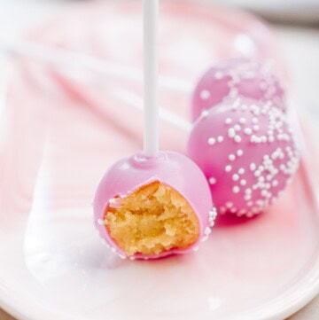 3 cake pops on a plate, one with a bite taken