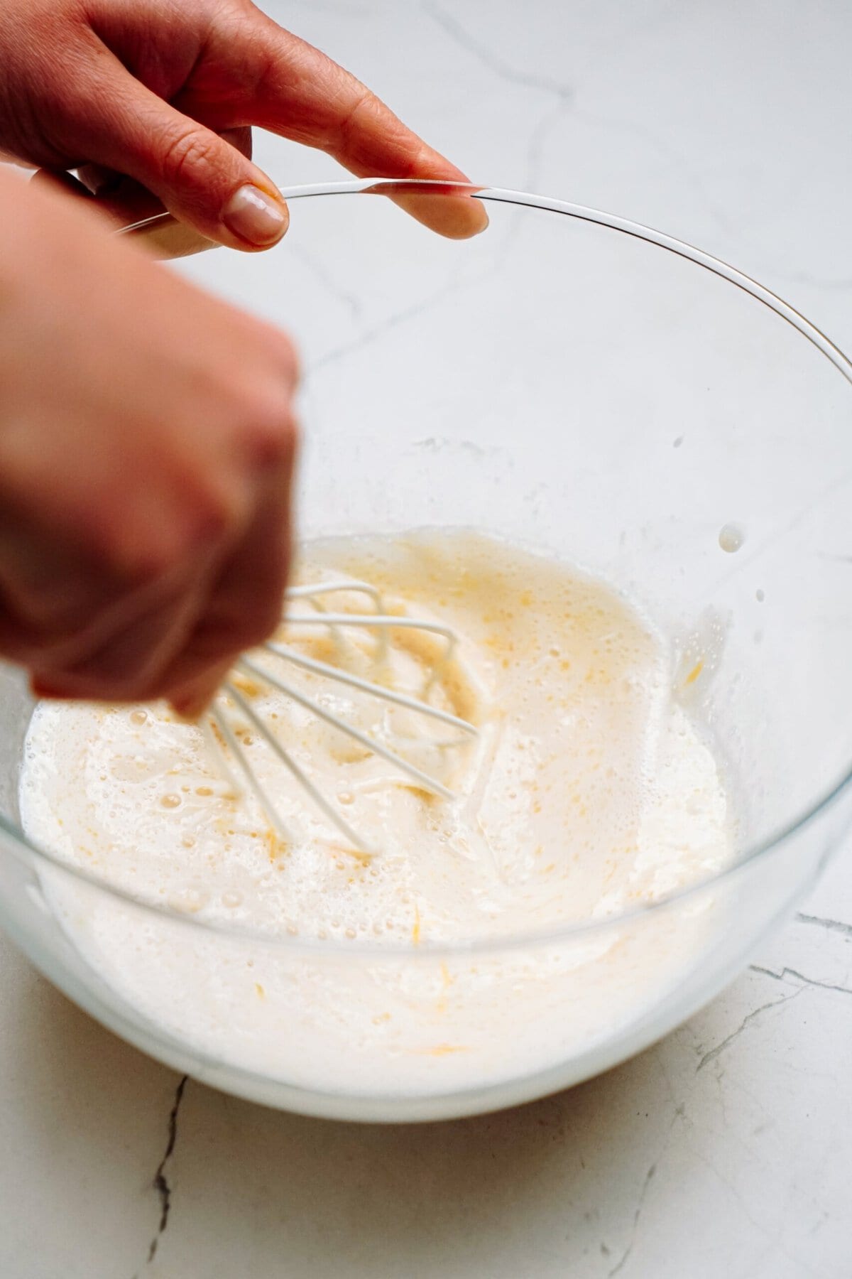 a person stirring yeast and melted butter together with a whisk