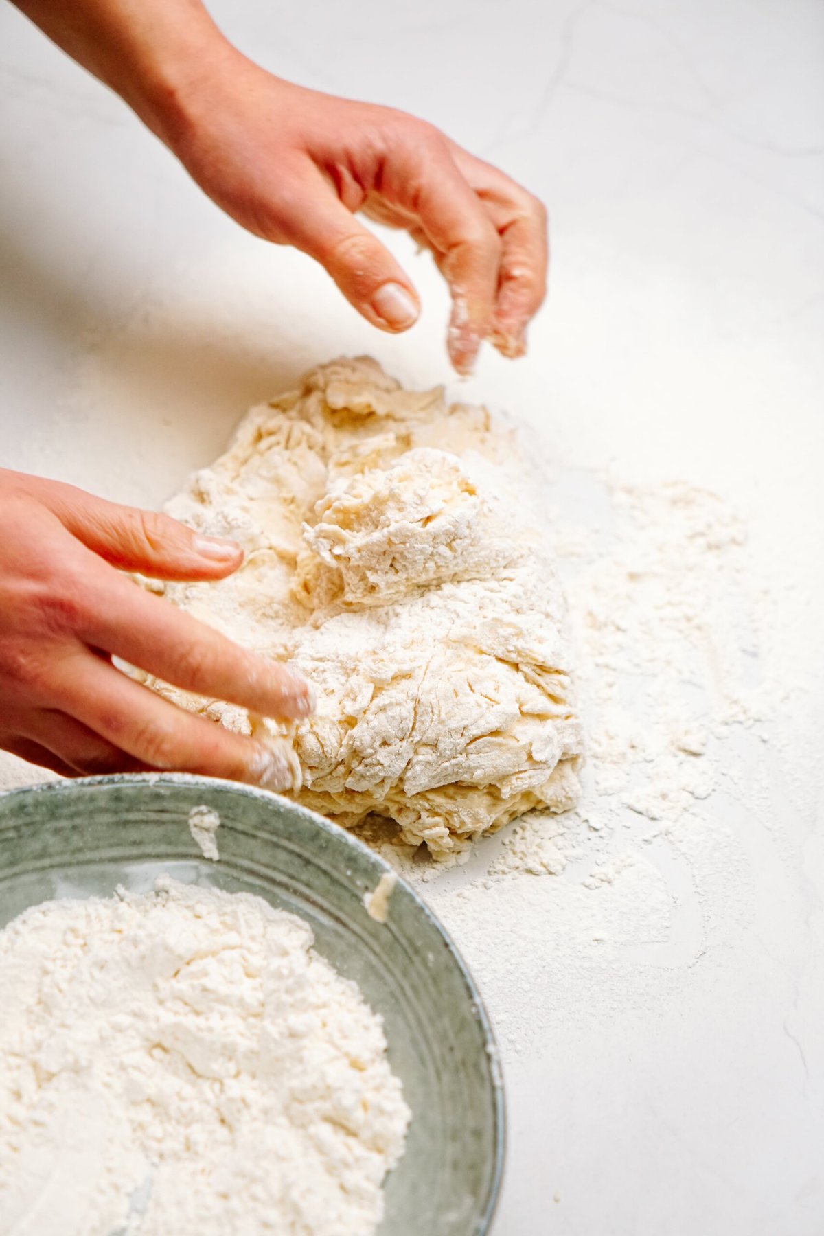 a person kneading dough on a floured counter