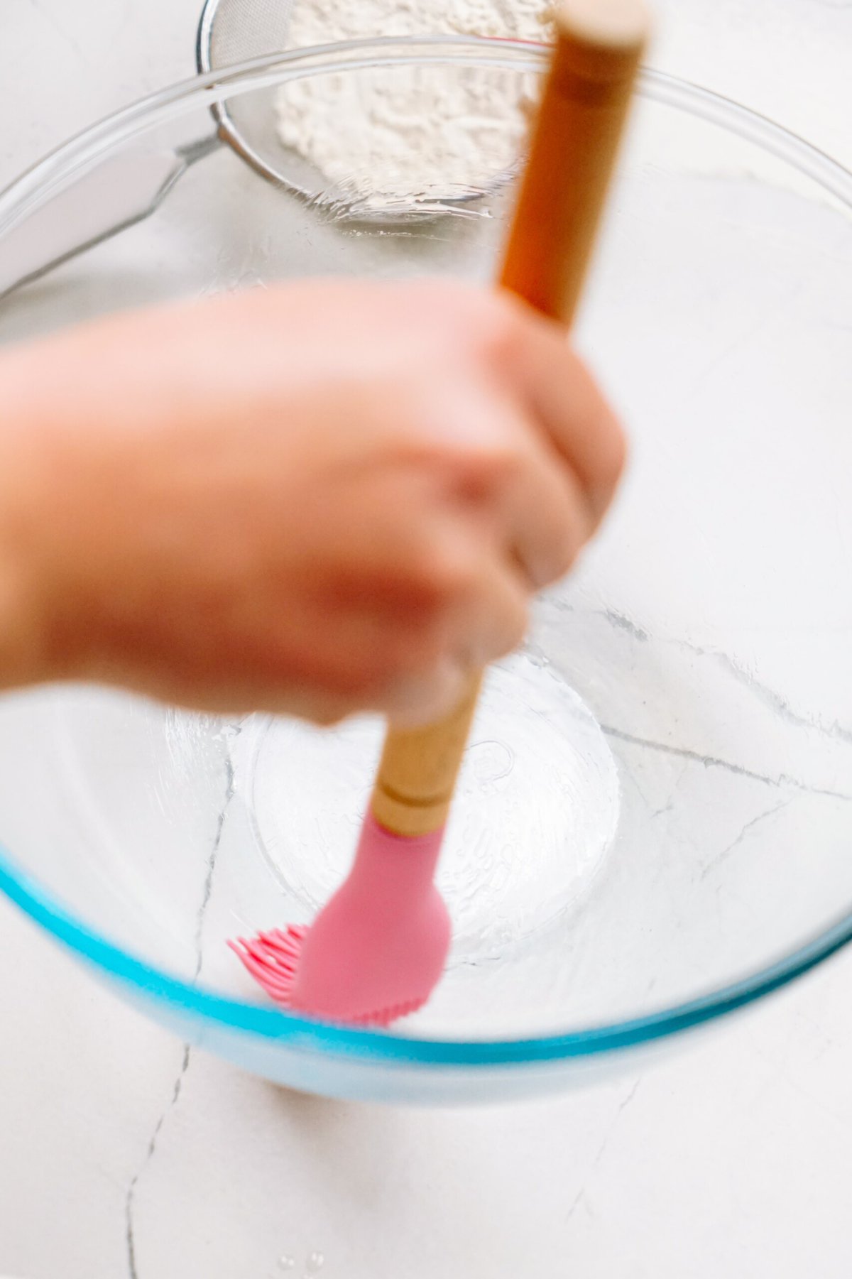 a person greasing a bowl with a brush