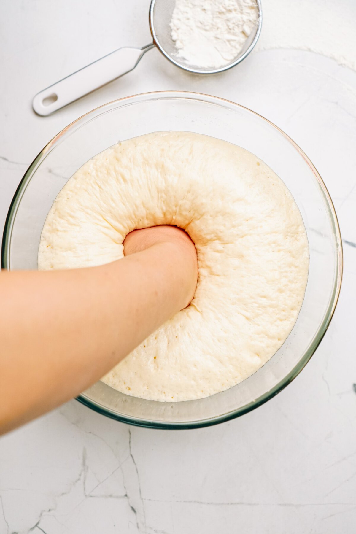 a person punching down the risen dough