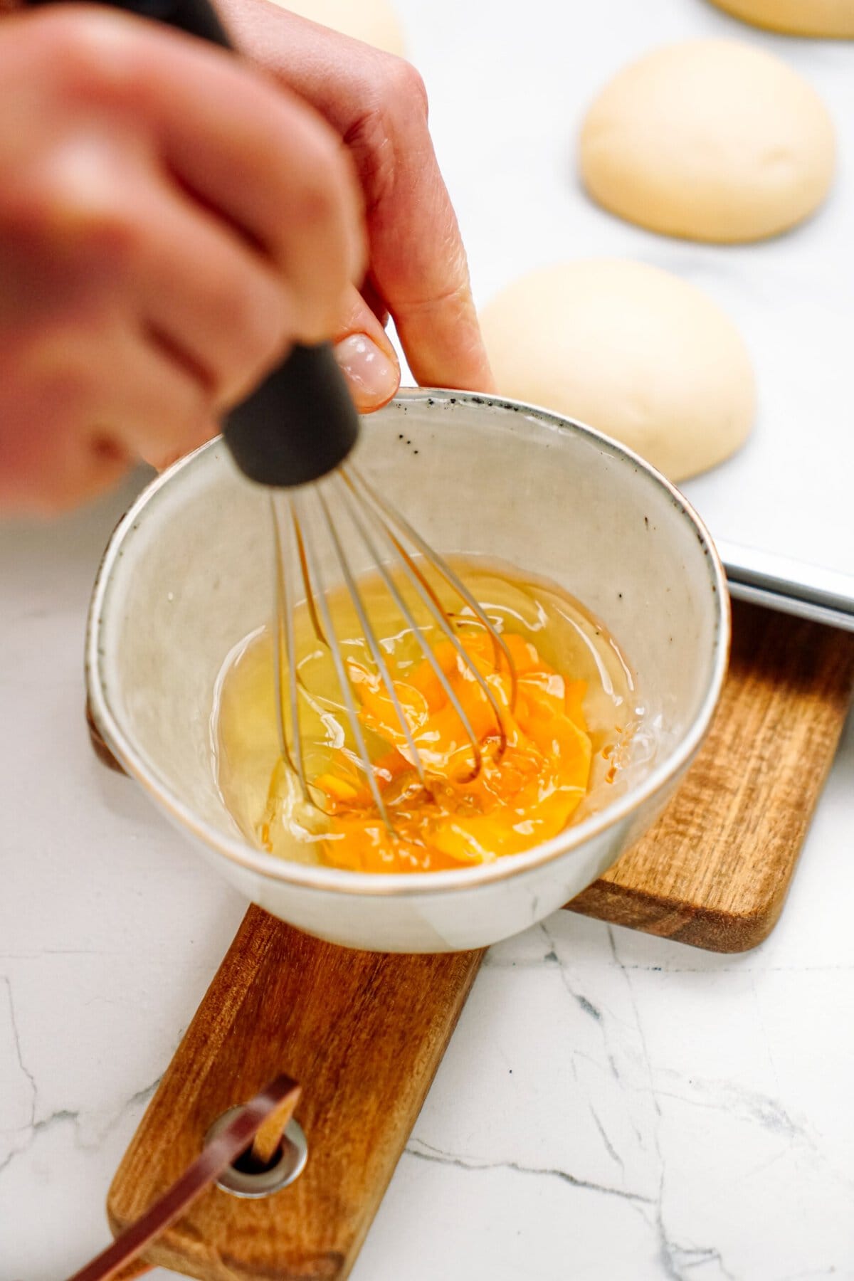 a person whisking an egg and water  in a bowl 