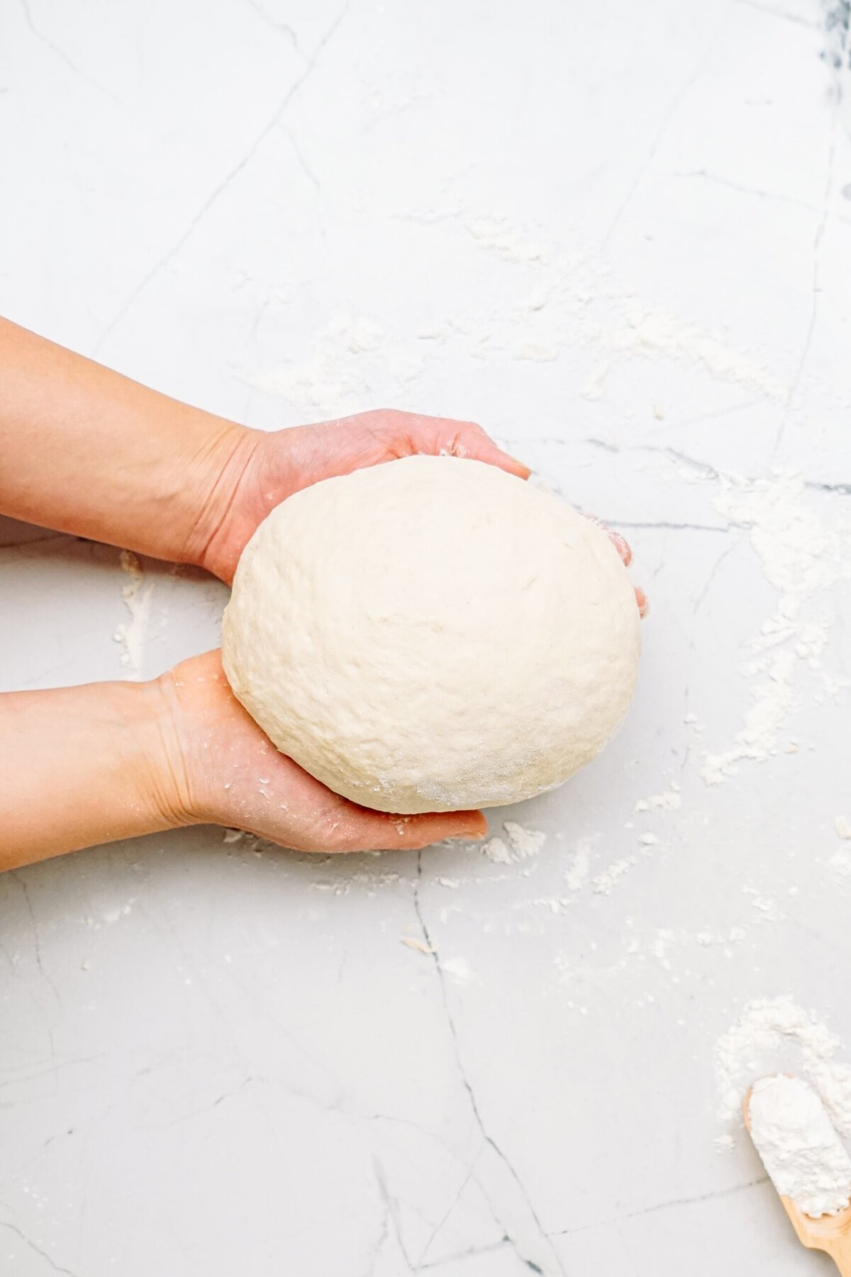 kneaded dough ball in a persons hands