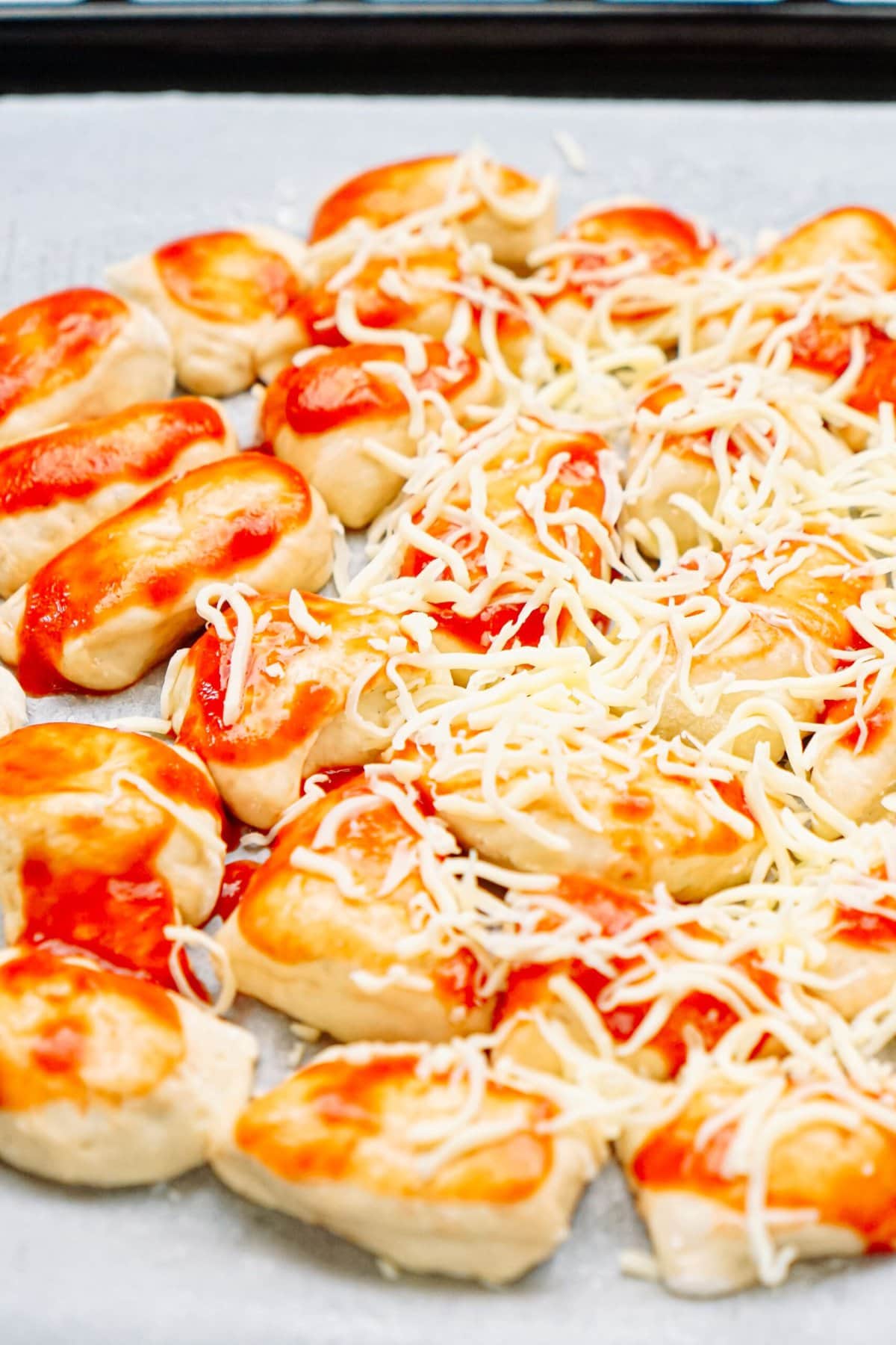 shredded mozzarella sprinkled onto pizza 