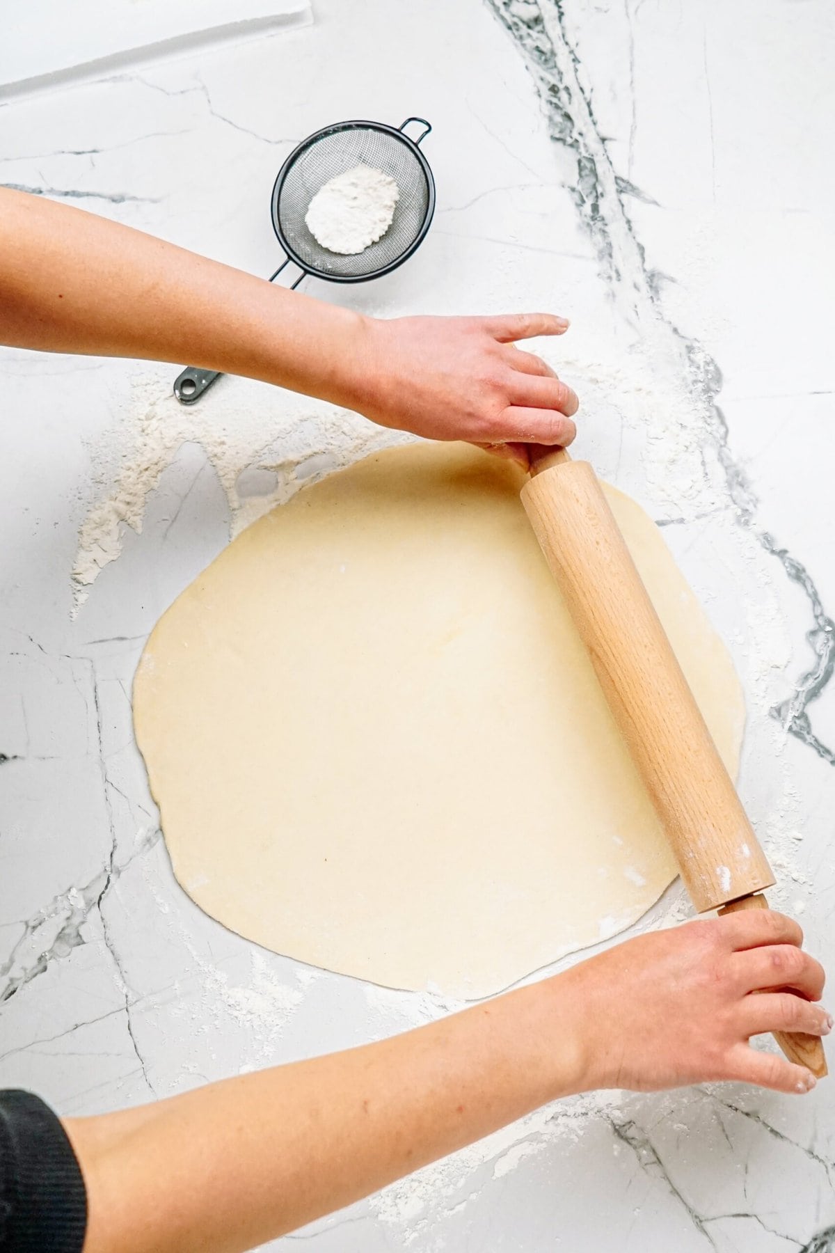 a person rolling out dough with a rolling pin 