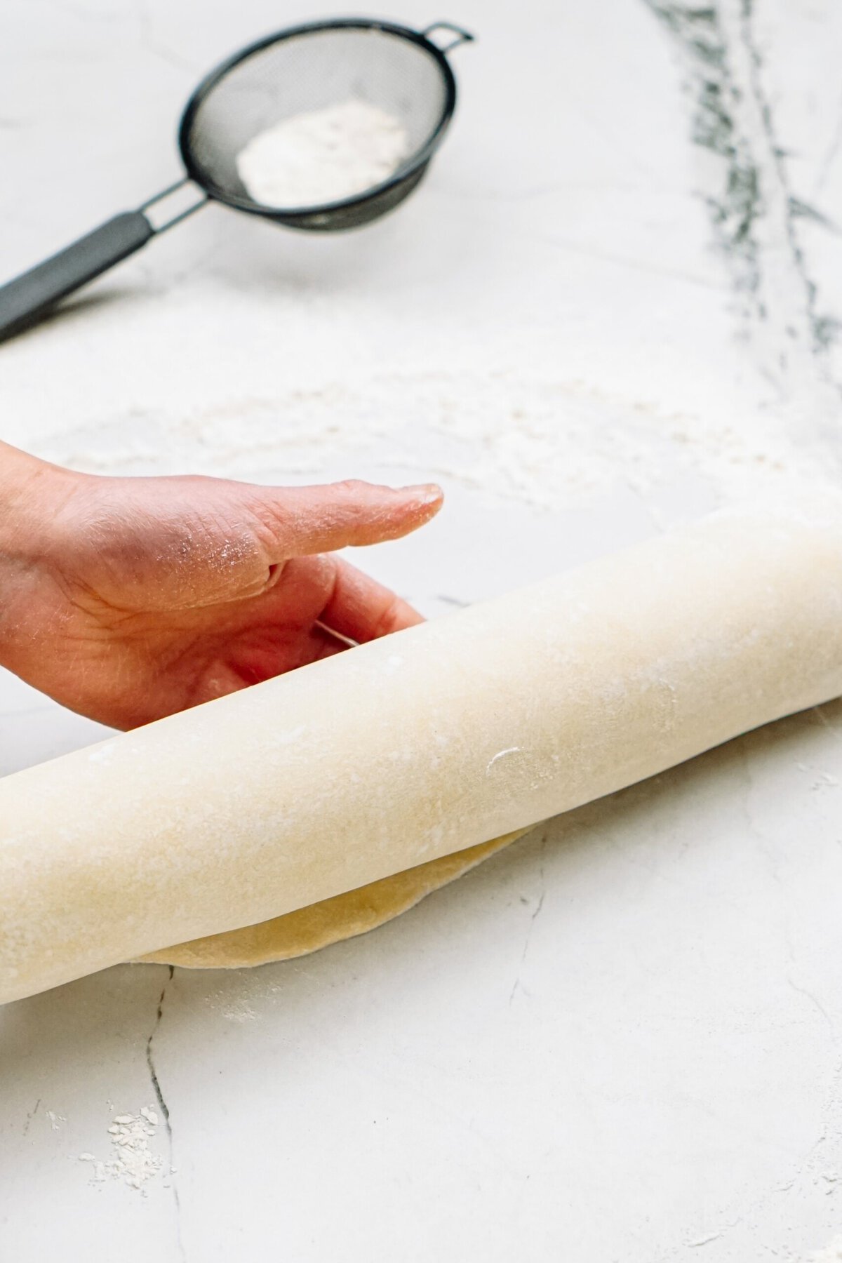 a person rolling dough onto a rolling pin 