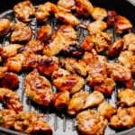 Grilled pieces of marinated Korean chicken cooking on a grill pan, with some pieces showing char marks.