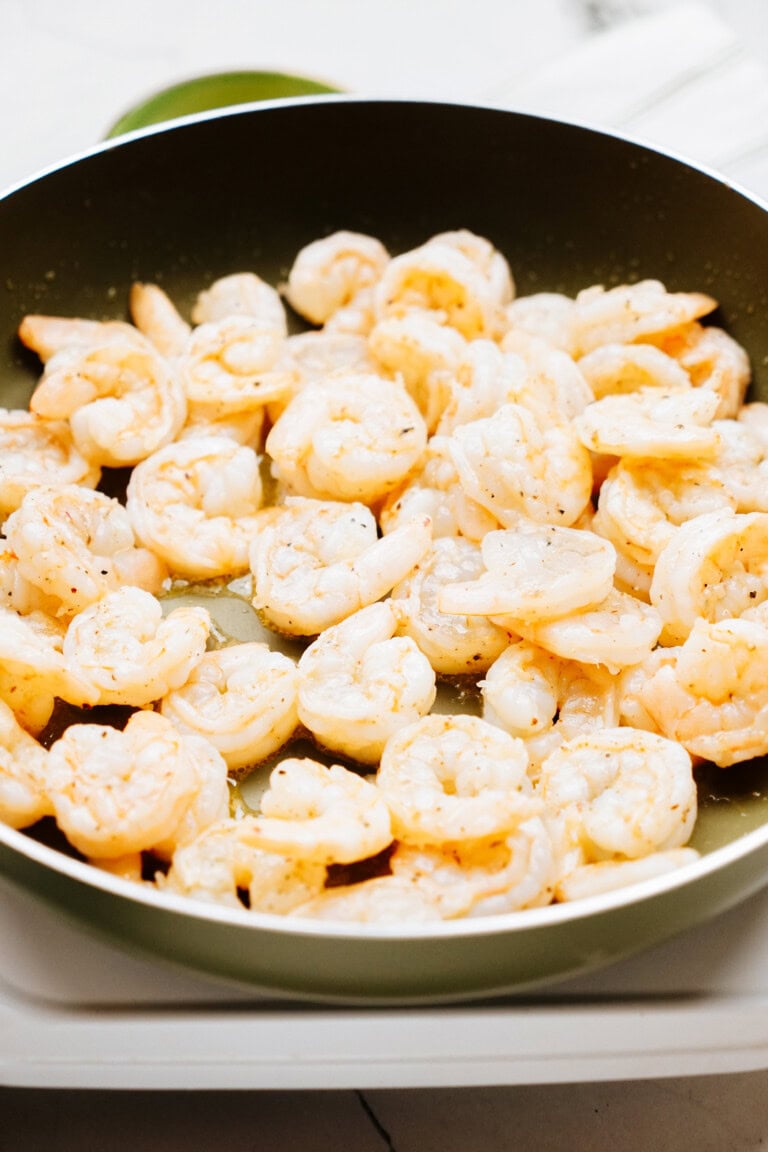 A frying pan filled with cooked shrimp.