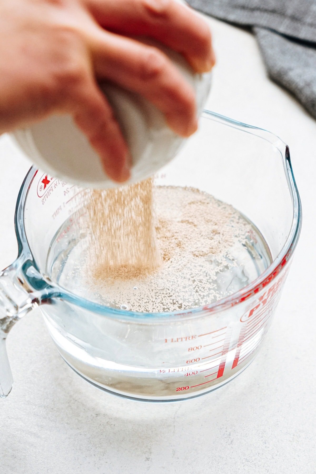 A person pouring yeast into a measuring cup.