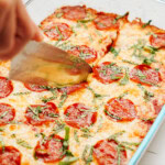 A Zucchini Pizza Casserole with pepperoni and cheese in a glass dish.