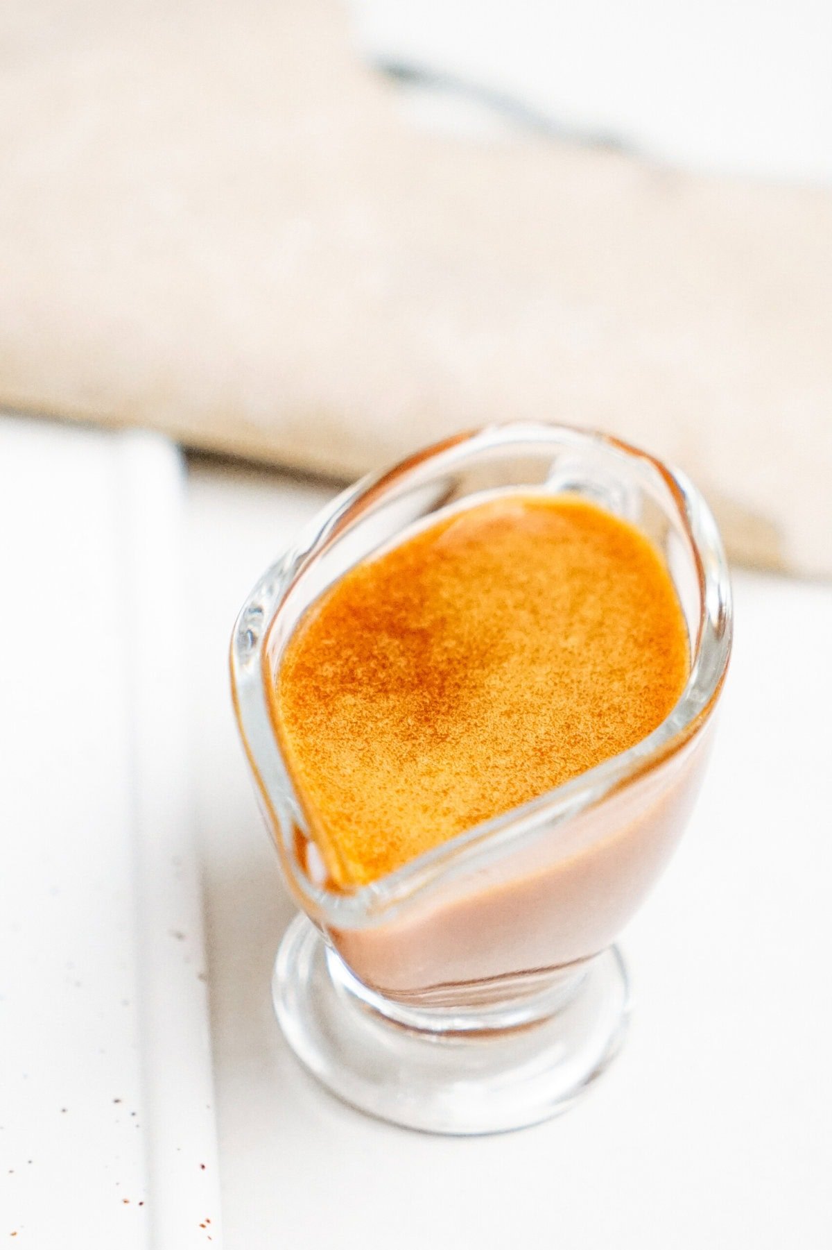 A glass container filled with caramel sauce placed on a white surface.