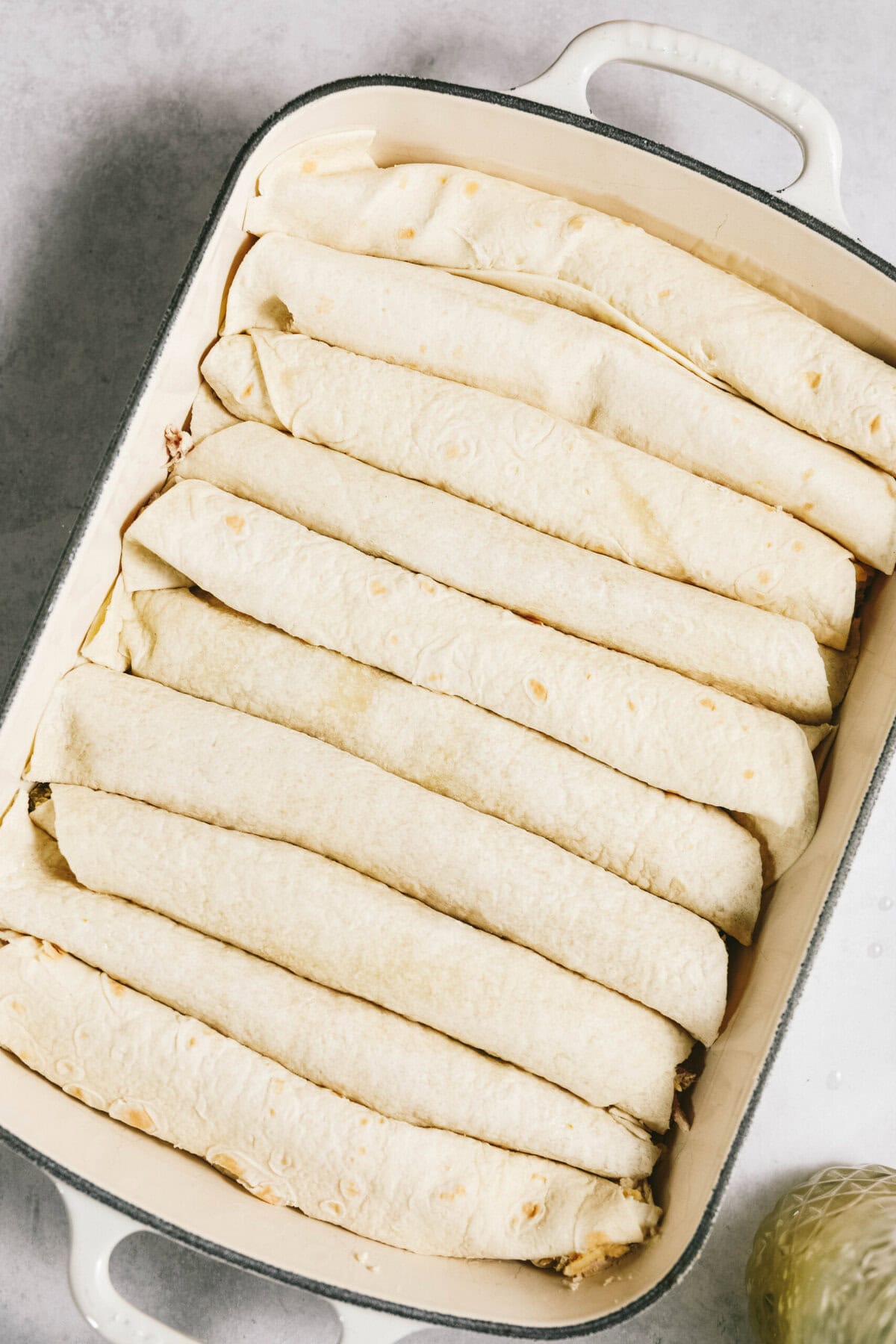 A casserole dish filled with neatly arranged, rolled flour tortillas.