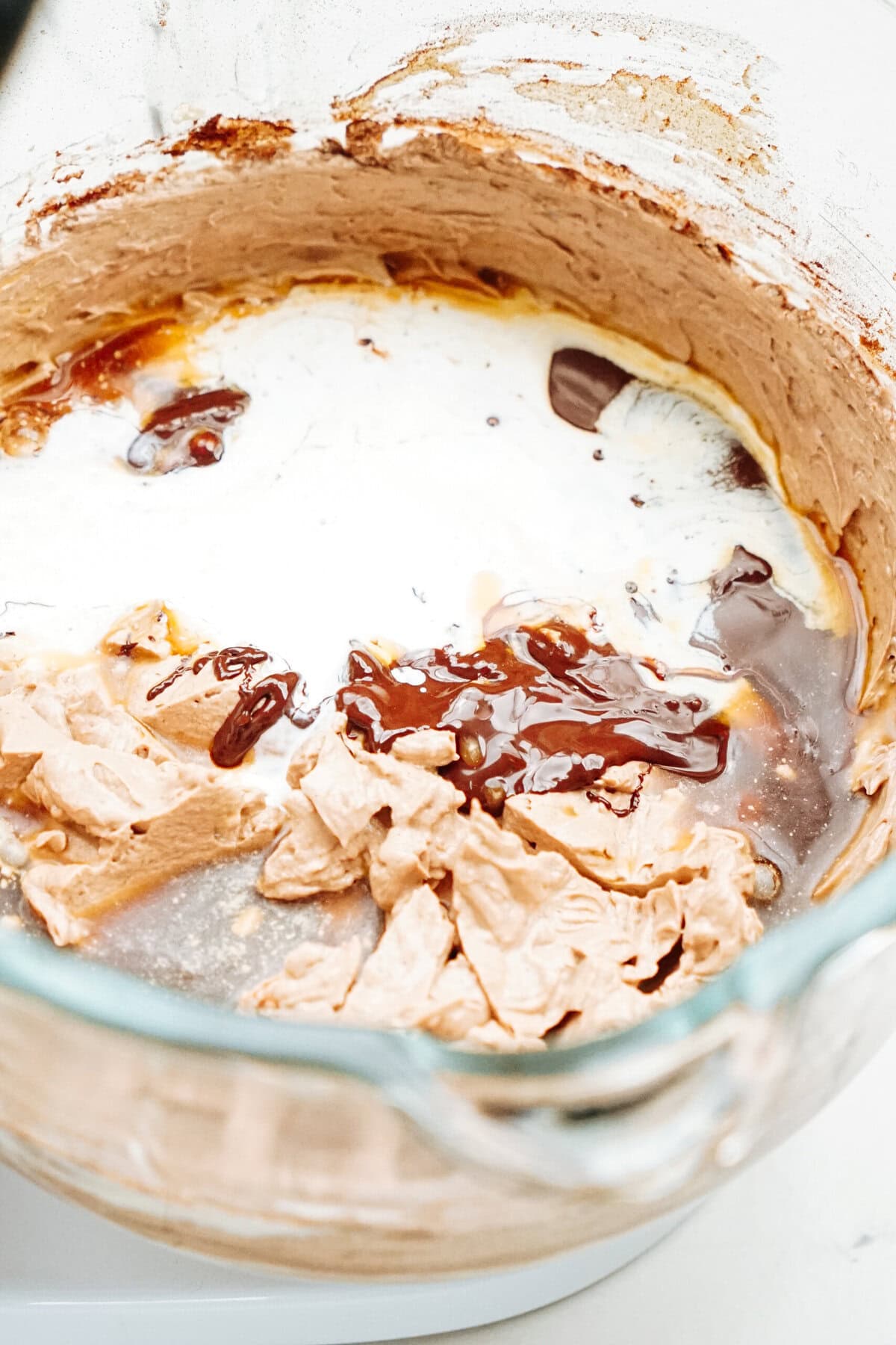 Mixing bowl with chocolate batter, melted chocolate, and cream being combined.