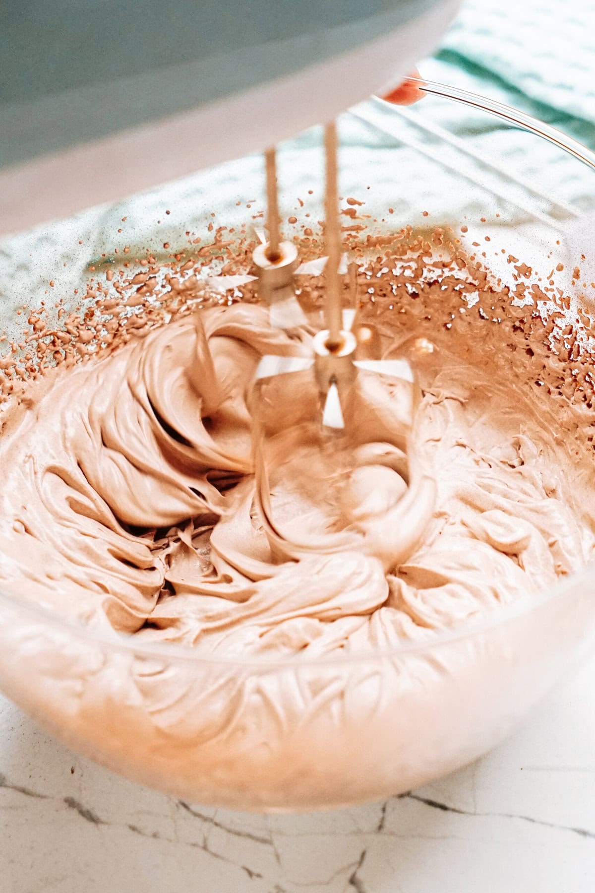 Mixer beaters spinning in a bowl of chocolate mousse, creating a light brown cream or batter.