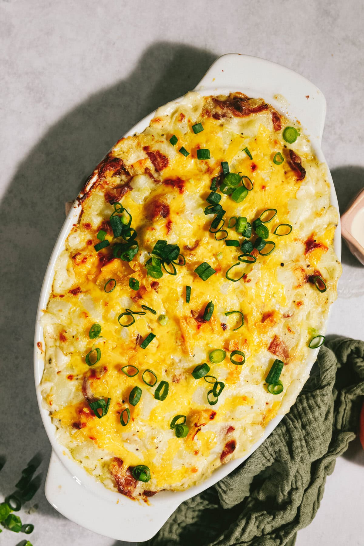 A baked dish in an oval casserole, topped with melted cheese and chopped green onions.