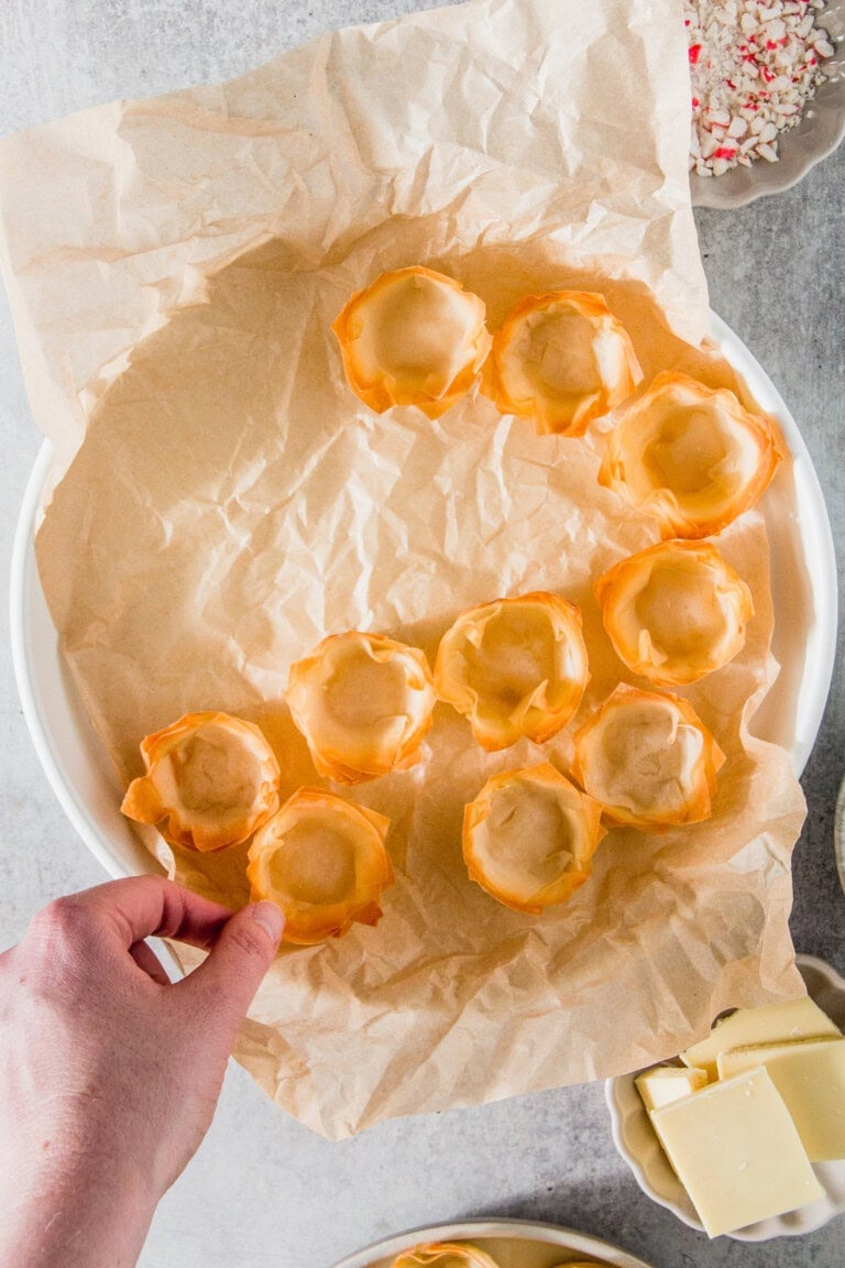 A person arranges empty waffle cups on a sheet of parchment paper.