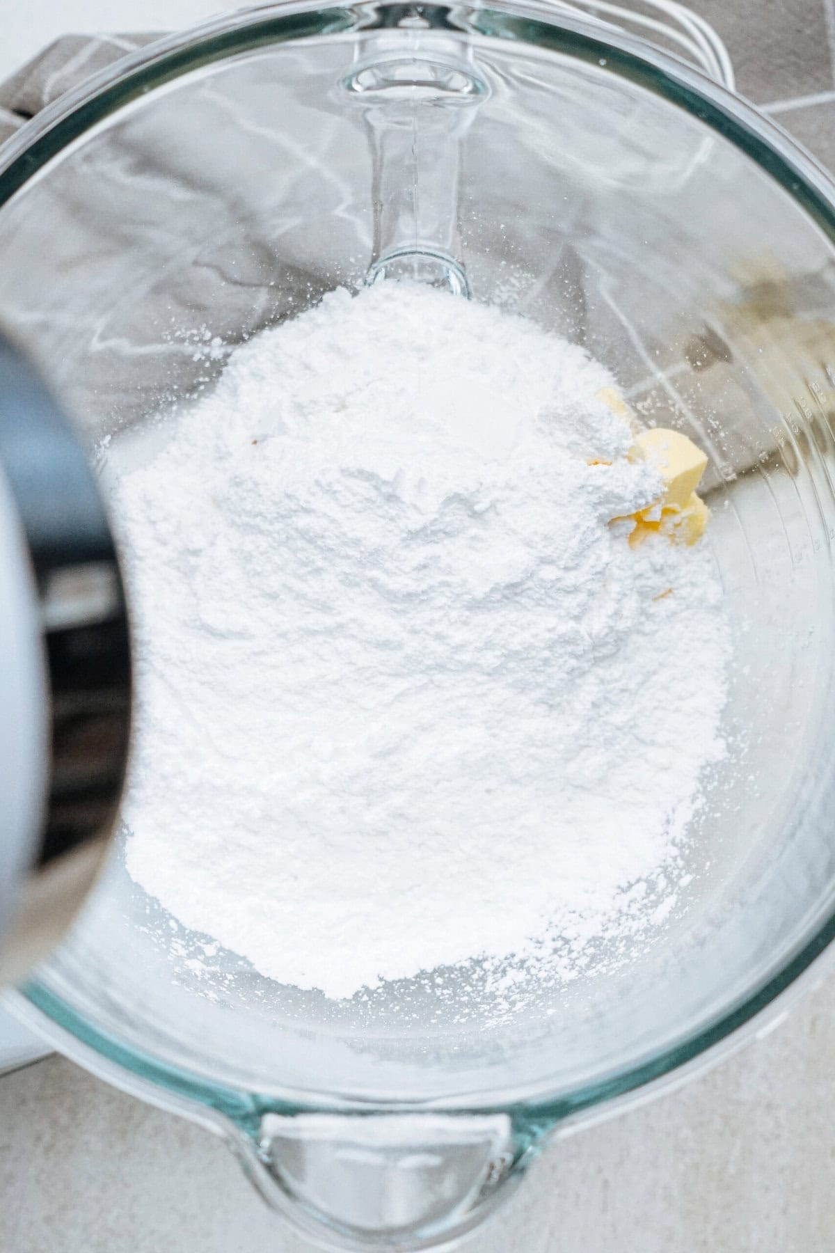 A glass mixing bowl containing flour and small chunks of butter.