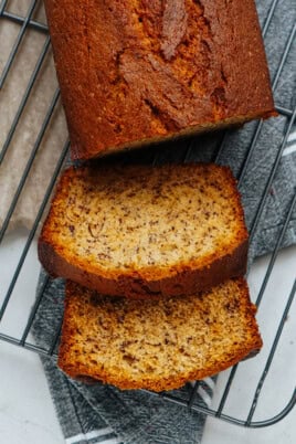 Sliced banana bread on a wire cooling rack with visible banana specks.