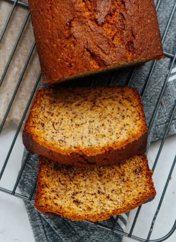 Sliced banana bread on a wire cooling rack with visible banana specks.