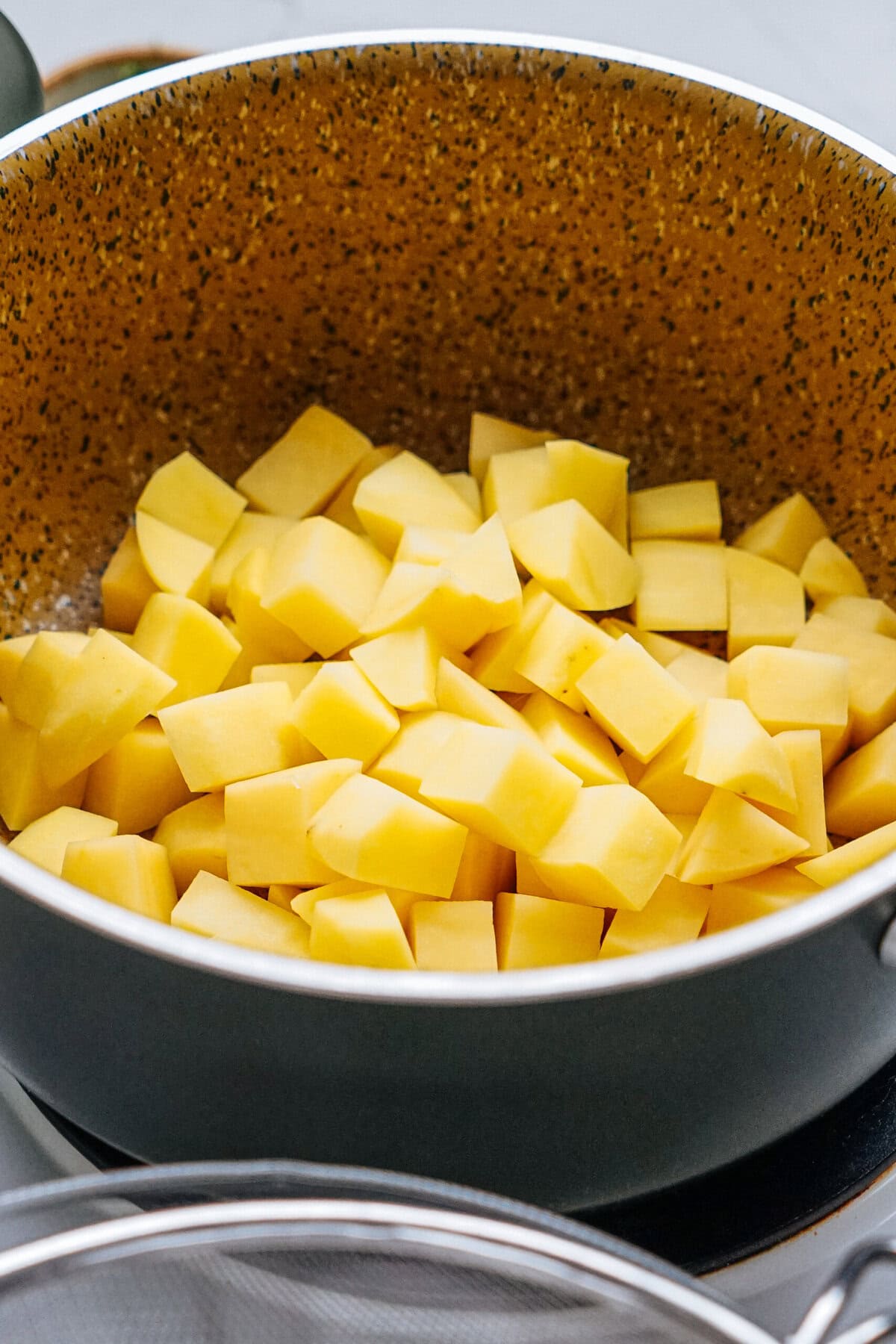 Cubed potatoes in a large granite-finish pot.