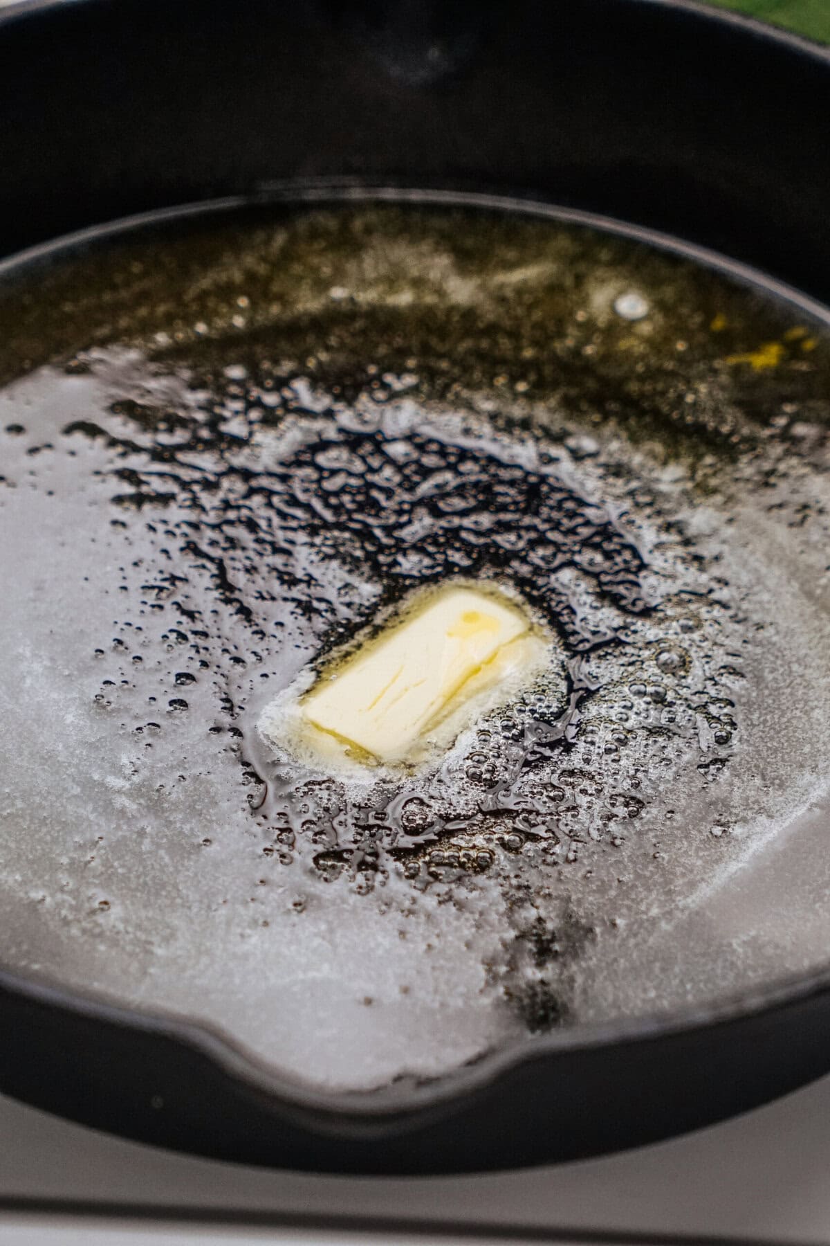 A pat of butter melting in a cast iron skillet.