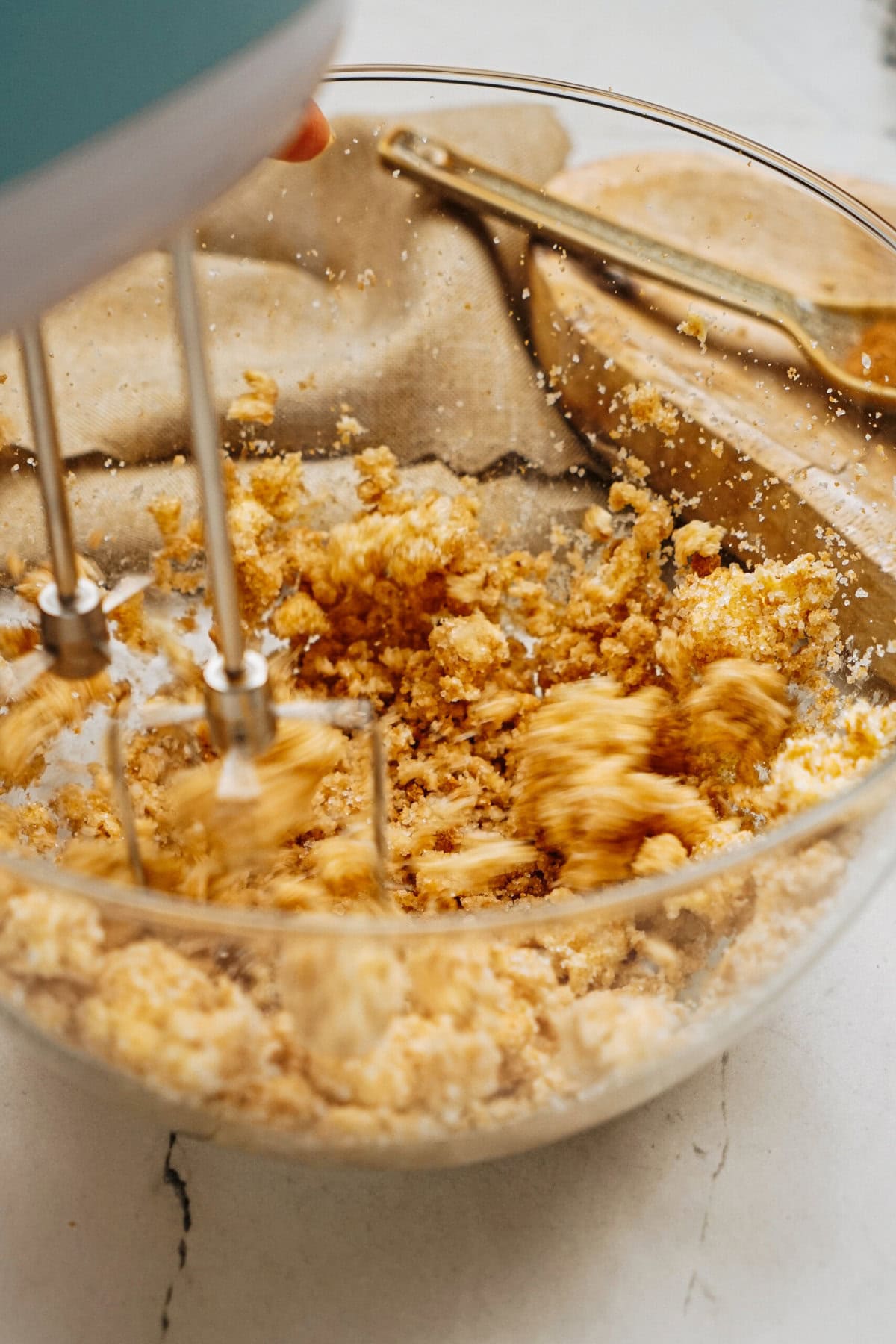 A mixer blends ingredients for delicious ginger cookies in a clear bowl on a kitchen counter.