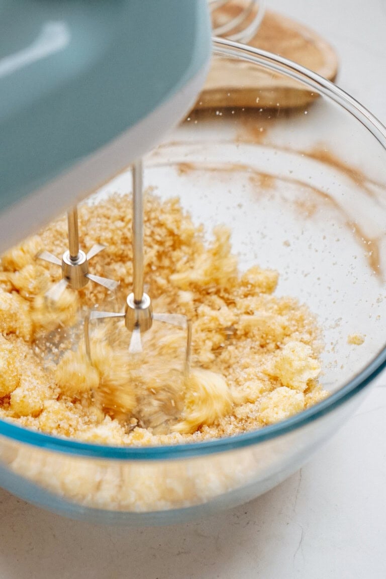 An electric mixer skillfully blends butter and sugar with the rich essence of gingerdoodle cookies in a clear glass bowl.