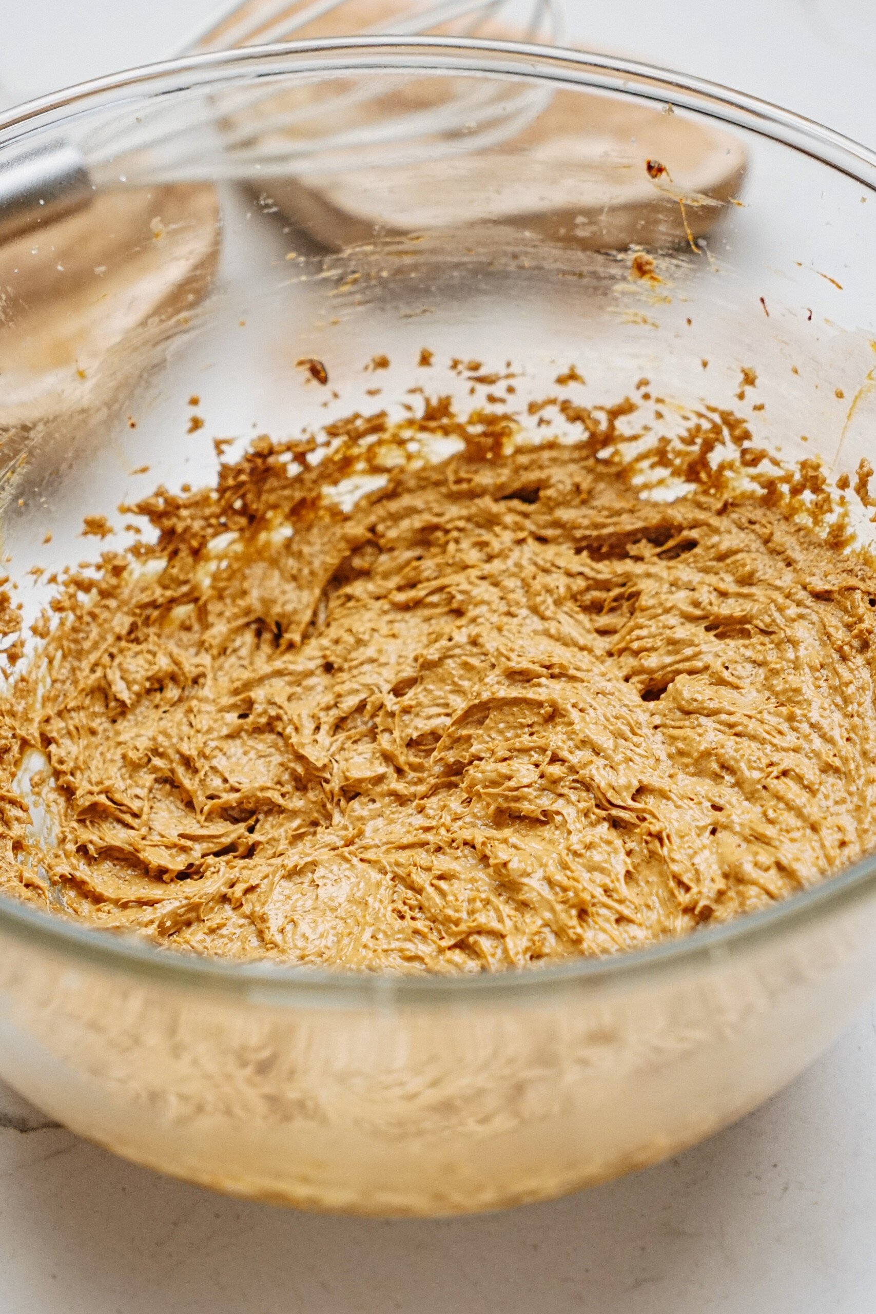 A glass bowl filled with a thick, brownish gingerdoodle cookies, likely for baking.