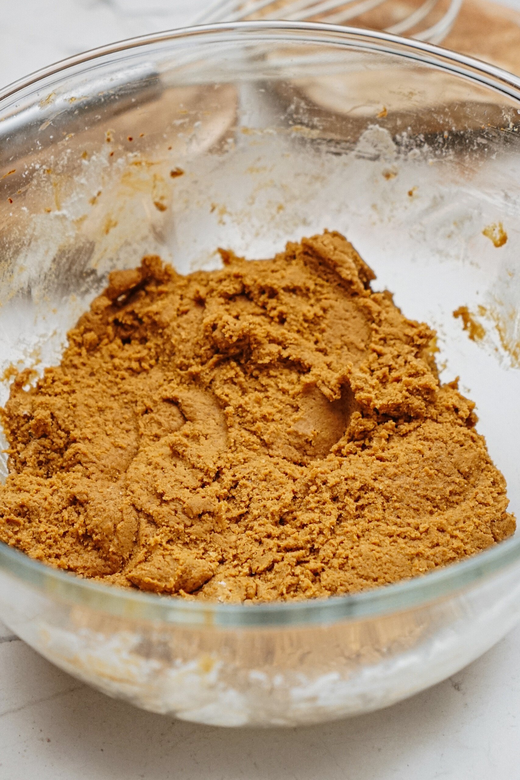 A clear glass bowl filled with brown dough sits on a kitchen counter.