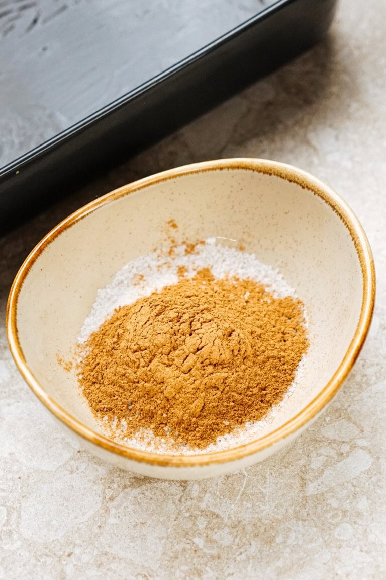 A small bowl contains a mound of brown powder on a countertop.