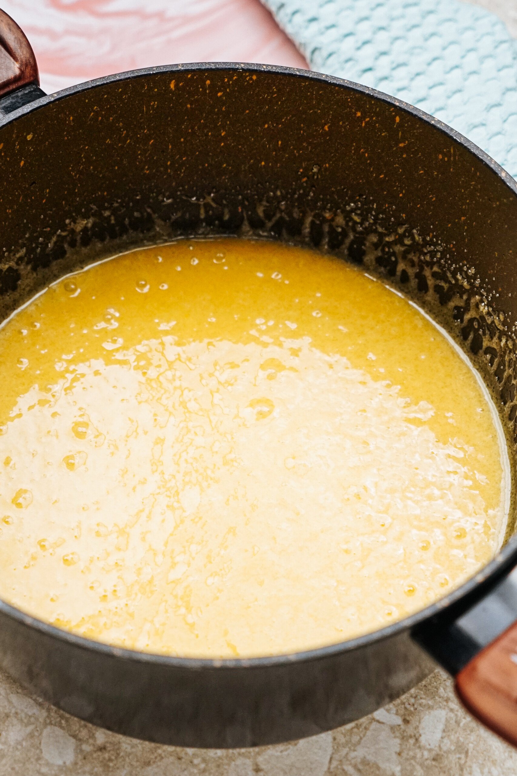 A pot filled with a thick, smooth yellow sauce placed on a countertop.