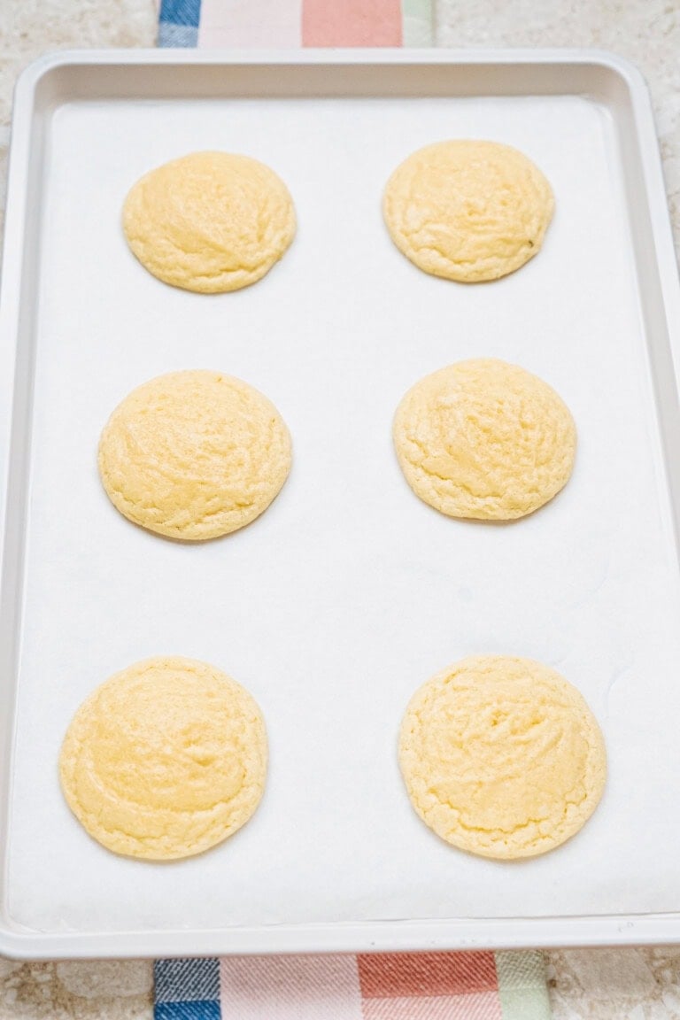 Six round cookies on a parchment-lined baking sheet.