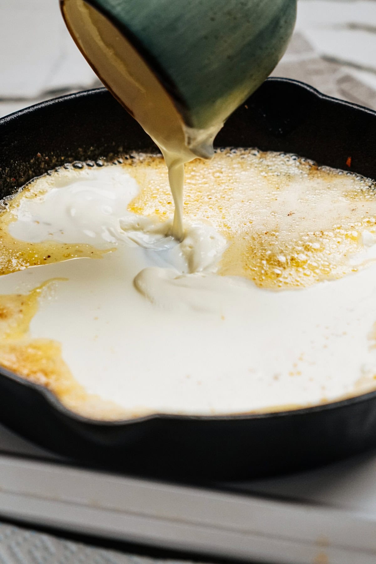 Cream being poured into a hot pan with sizzling melted butter, creating the perfect base for a mouthwatering Sausage Alfredo.