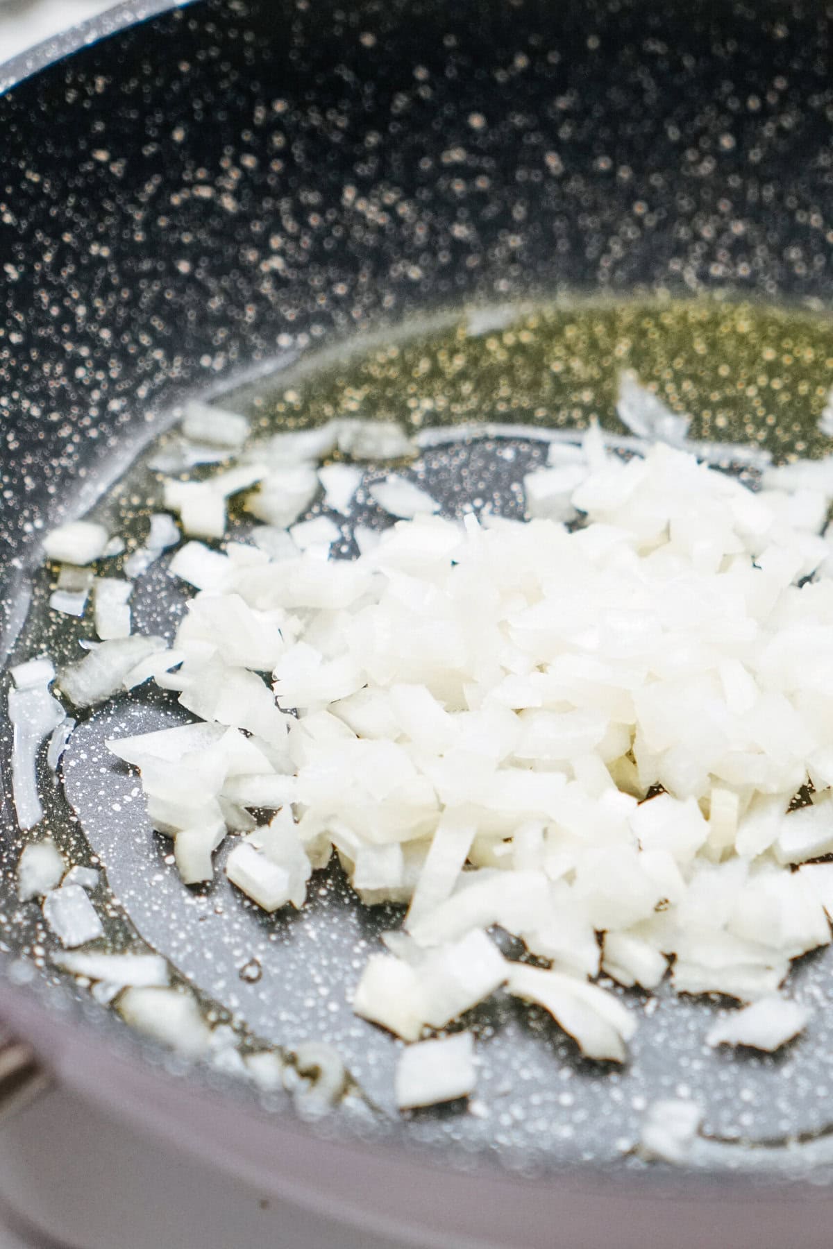 Diced onions sizzle in a black skillet with oil, creating the perfect base for a delicious stir fry.